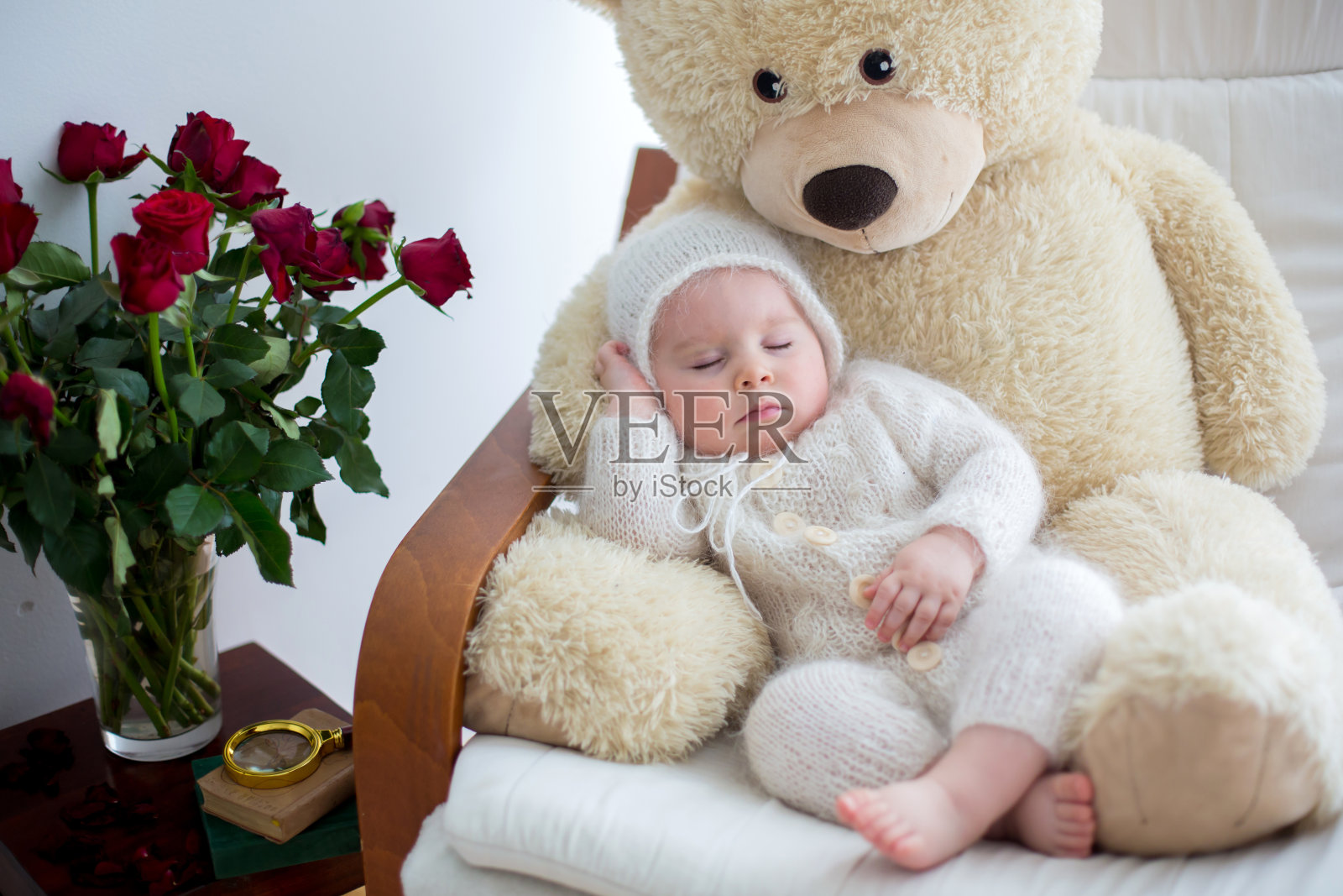 可爱的小男孩，和巨大的泰迪熊睡在大扶手椅上照片摄影图片