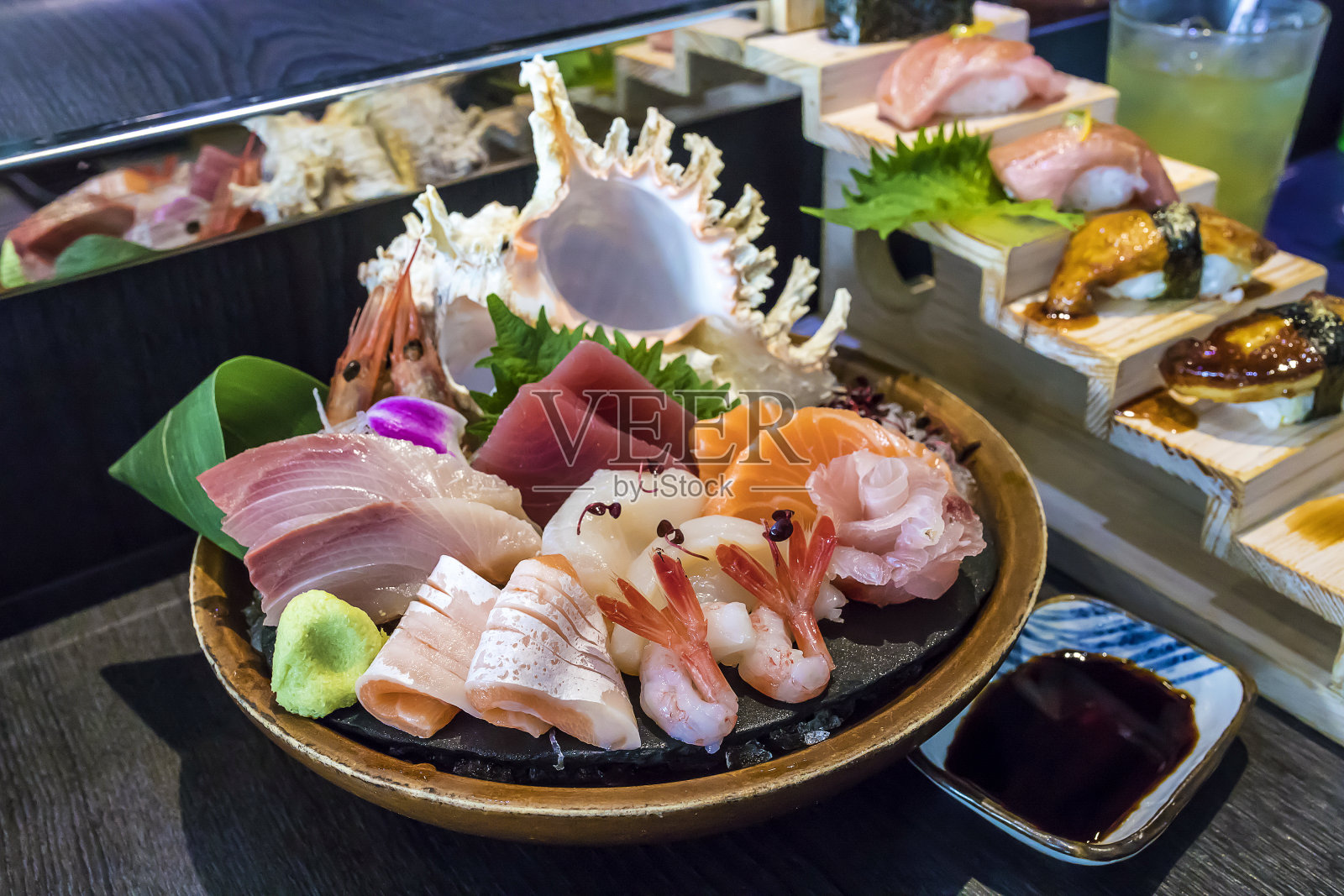 选择性聚焦装饰生鱼片放在碗与冰和海螺壳另一个寿司后面照片摄影图片