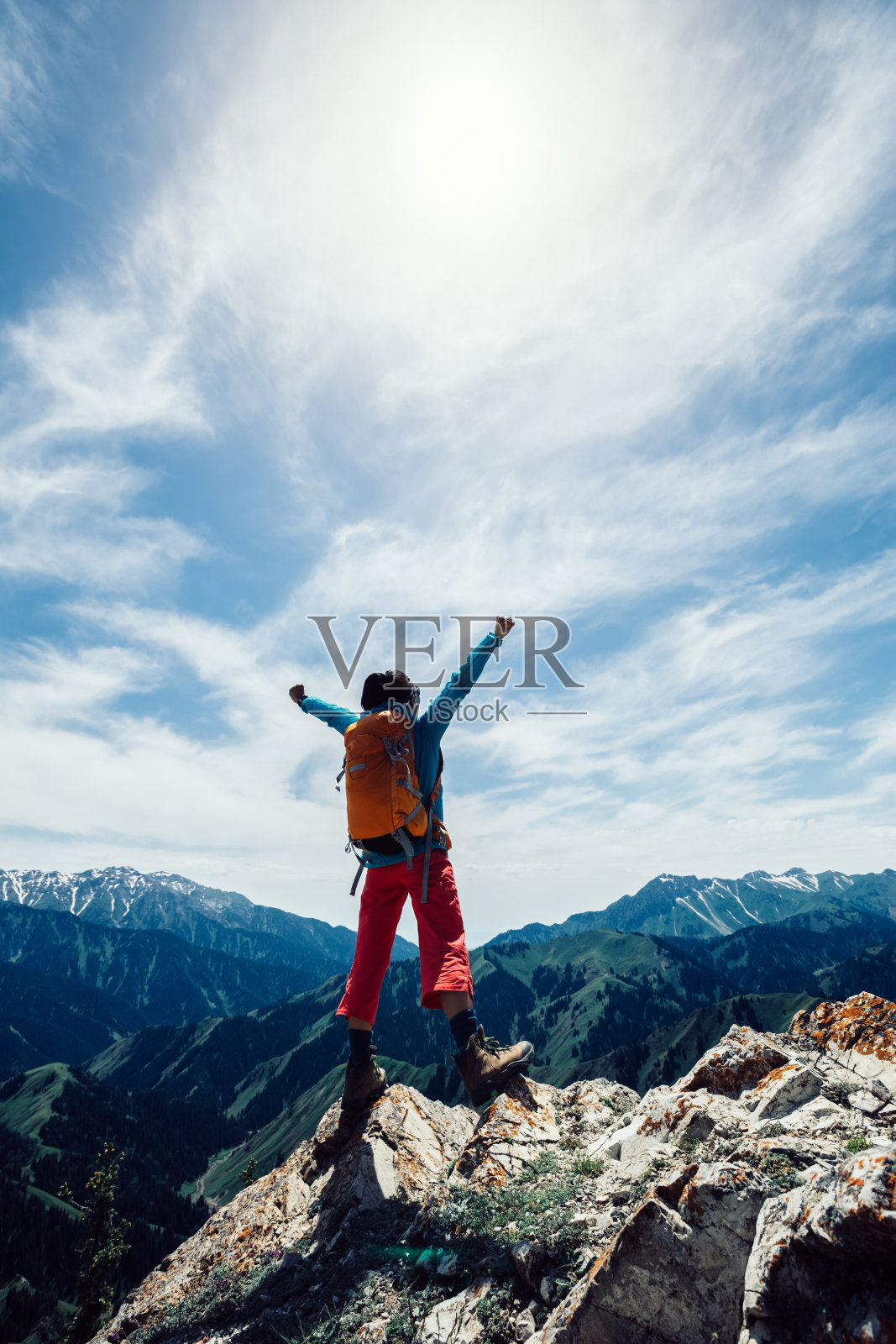 成功的徒步者伸开双臂站在山顶的悬崖边缘照片摄影图片