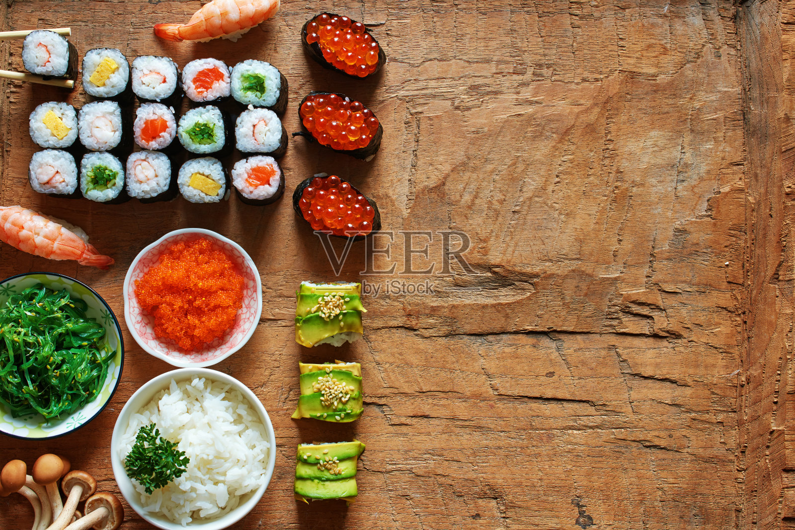 什锦寿司，煎蛋卷，虾，鲑鱼，鱼子酱和裙带菜，一碗米饭，木桌上的tobiko。平躺与文本空间。照片摄影图片