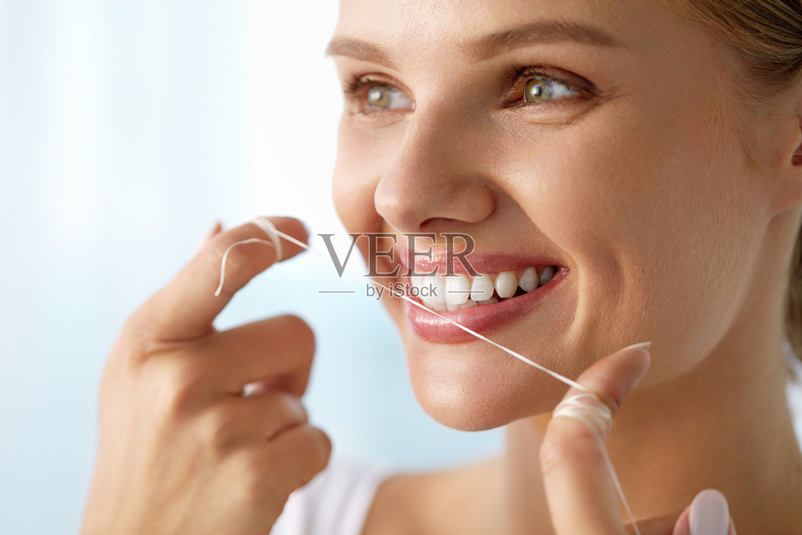 牙齿保健。美丽微笑的女人用牙线清洁健康洁白的牙齿照片摄影图片