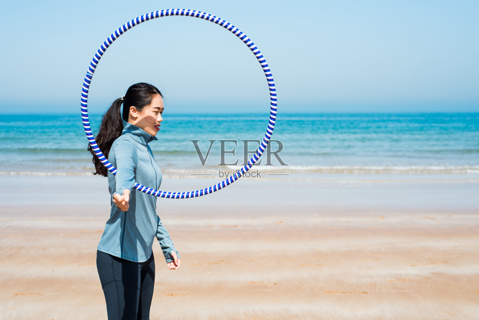 快乐的女人和呼啦圈在海滩上照片摄影图片