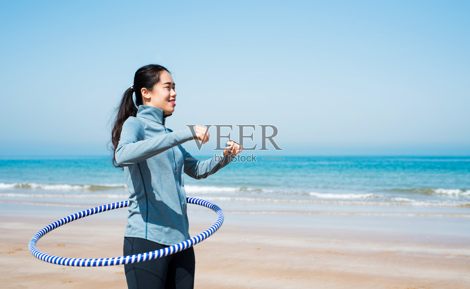 女孩在沙滩上用呼啦圈锻炼照片摄影图片