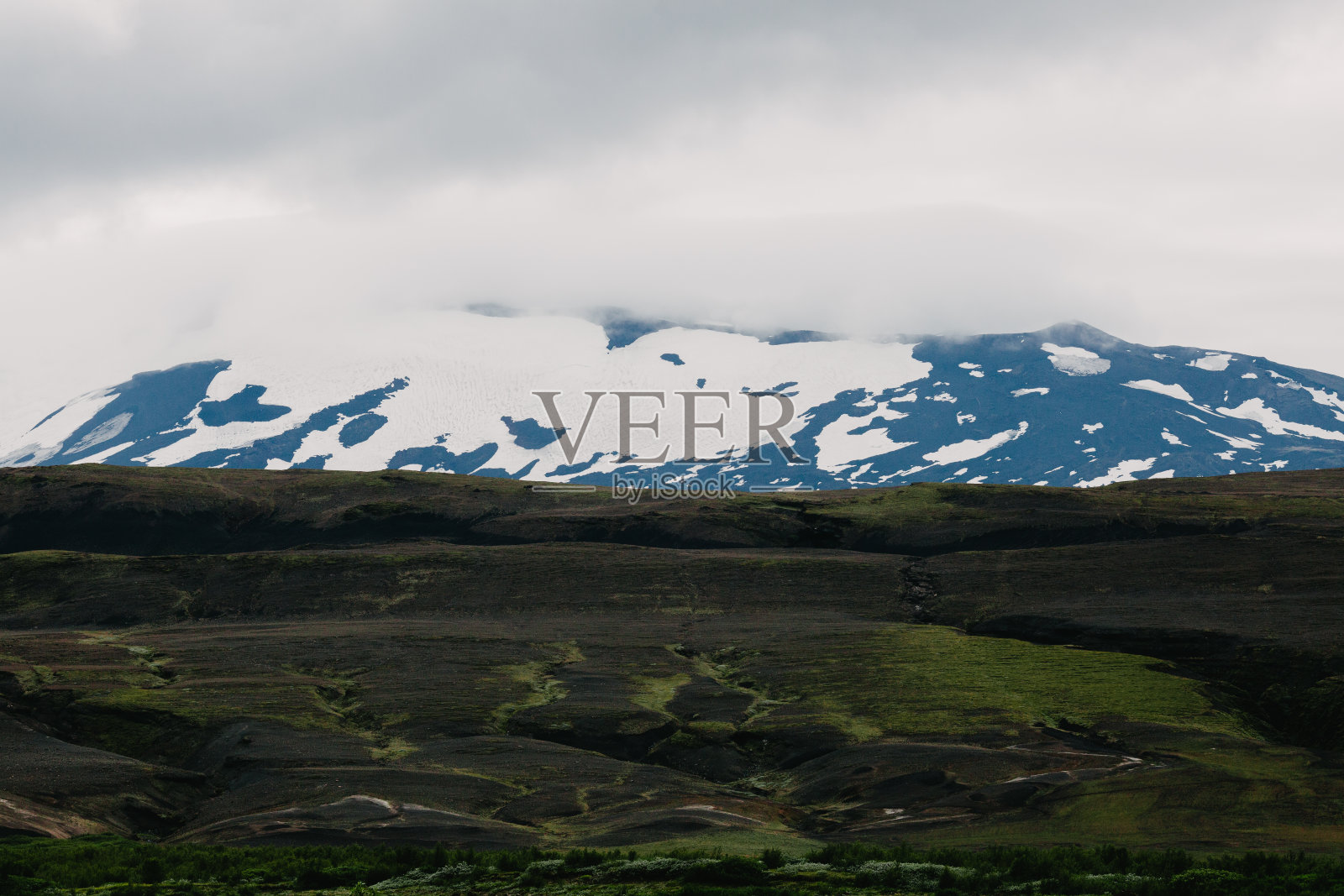 Landmannalaugar，冰岛，美丽的冰岛风景，黑色的地面上绿草和地平线上白雪覆盖的山脉照片摄影图片