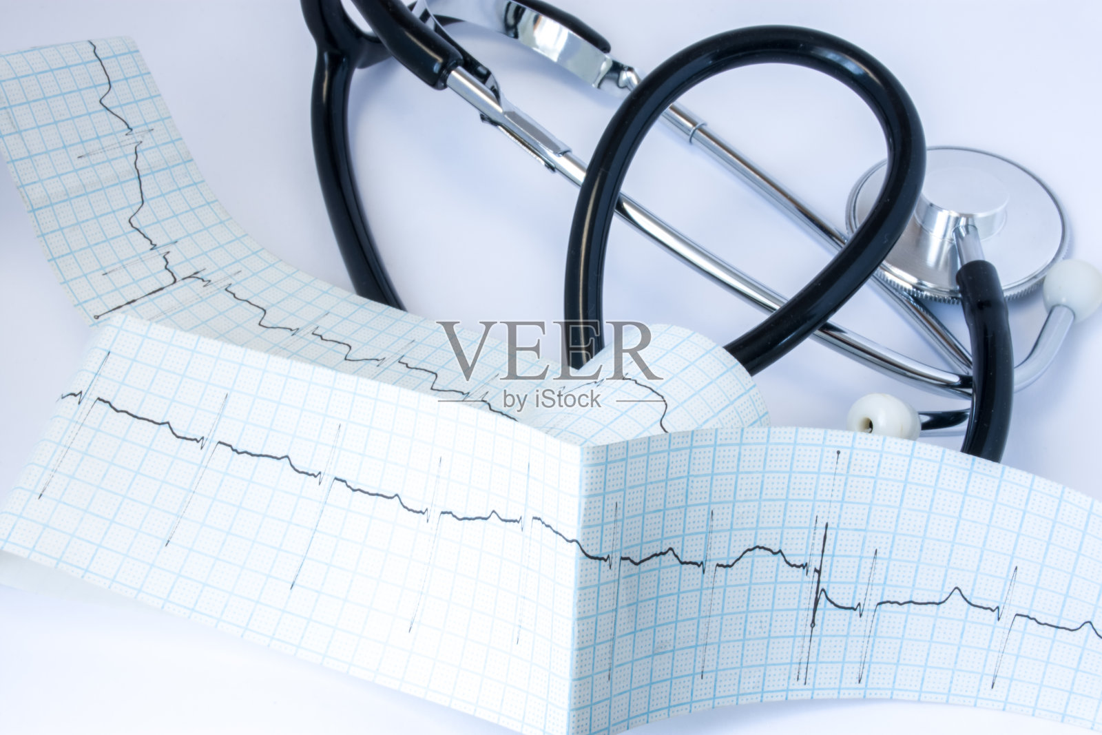 在心脏病医生或全科医生的办公室里，位于心电图带附近的黑色风管听诊器，在桌子上有一条脉搏迹线照片摄影图片