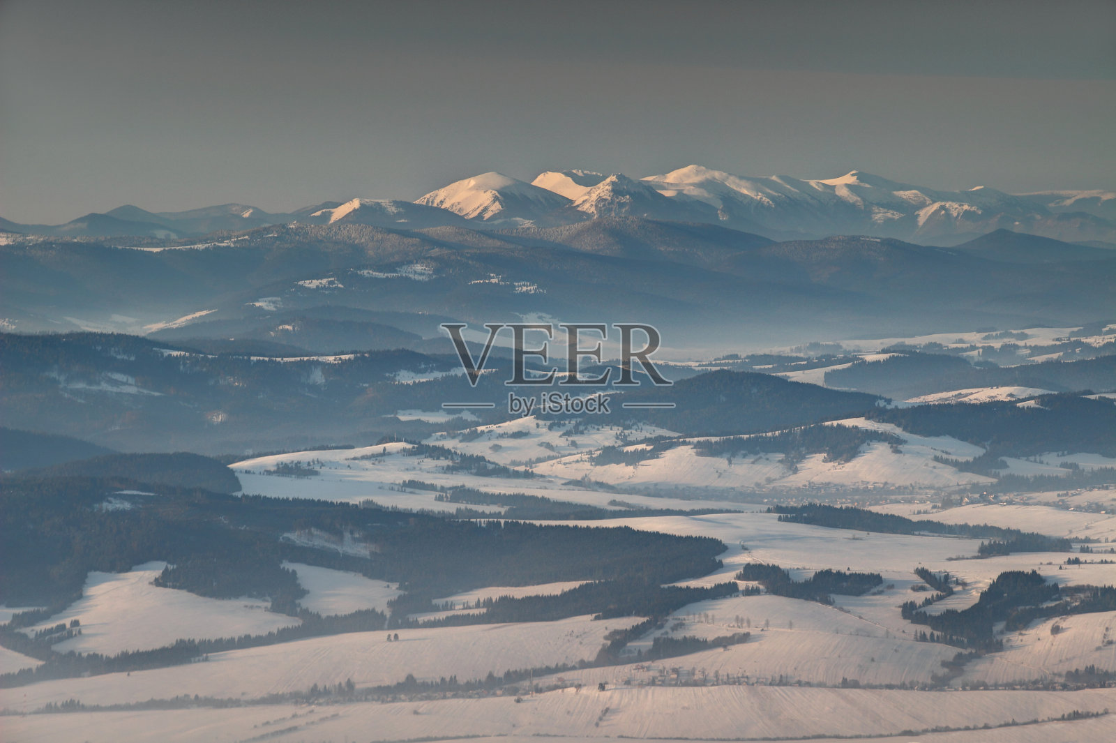 在日出的斯洛伐克，白雪覆盖的小法特拉山峰和薄雾中的森林照片摄影图片