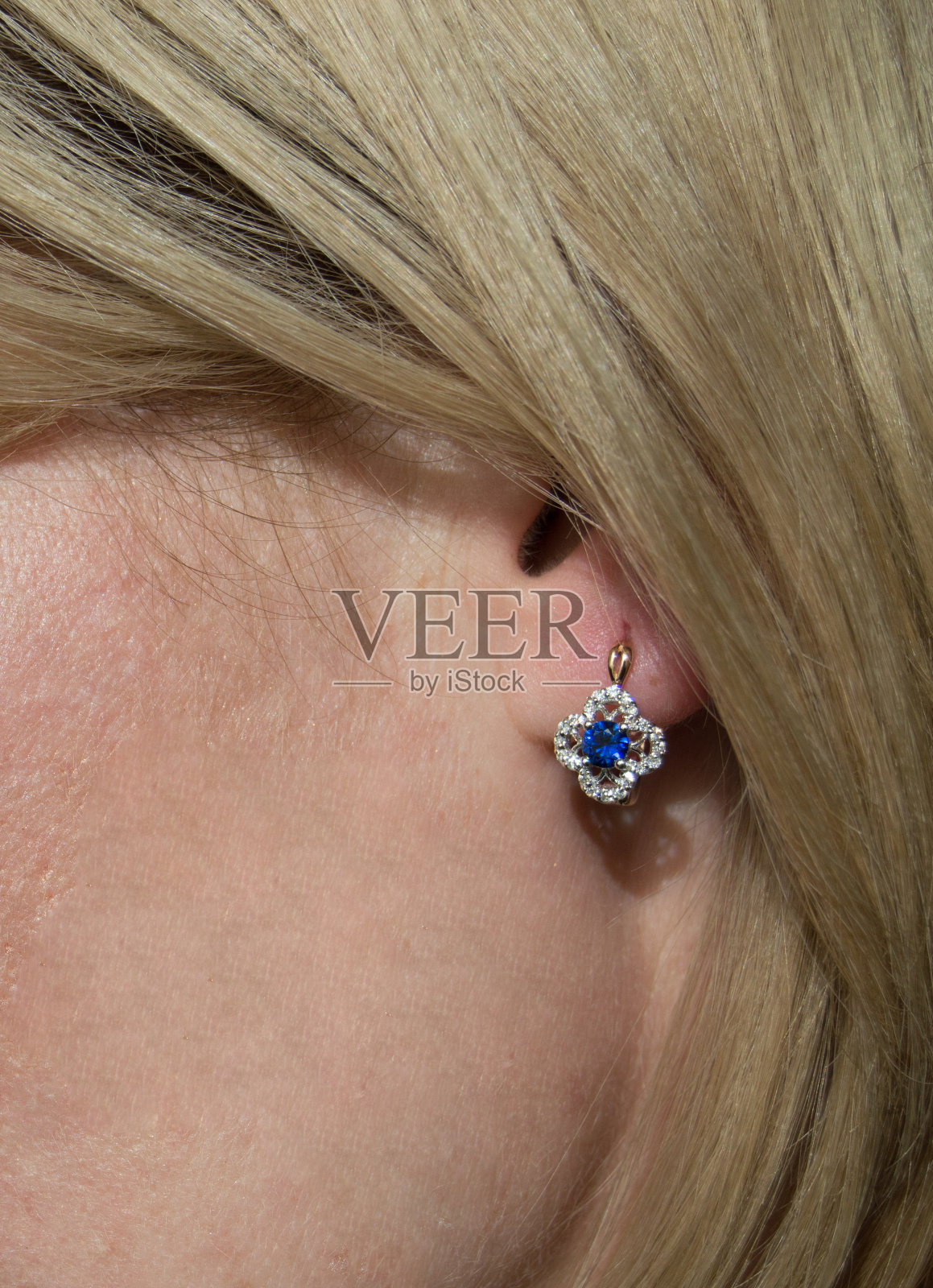 模型的耳朵上镶有深蓝色蓝宝石和几颗钻石的金色耳环照片摄影图片