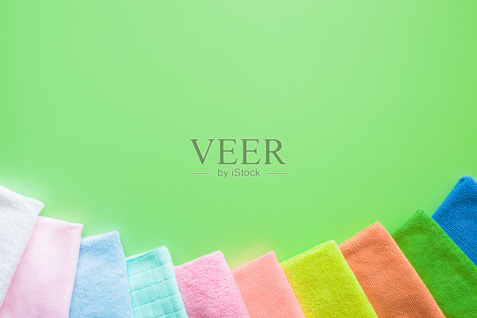 色彩鲜艳，干燥的超细纤维布，用于厨房，浴室和其他房间的不同表面清洁。绿色背景上文字或标志的空白位置。清洁服务理念。定期清理。照片摄影图片