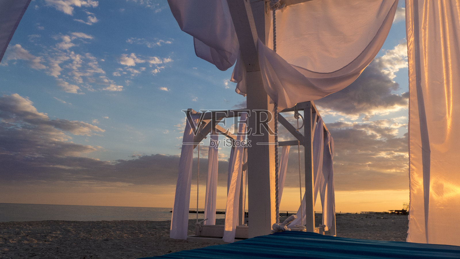 傍晚，在海滩上用白色织物窗帘搭起的遮阳篷照片摄影图片