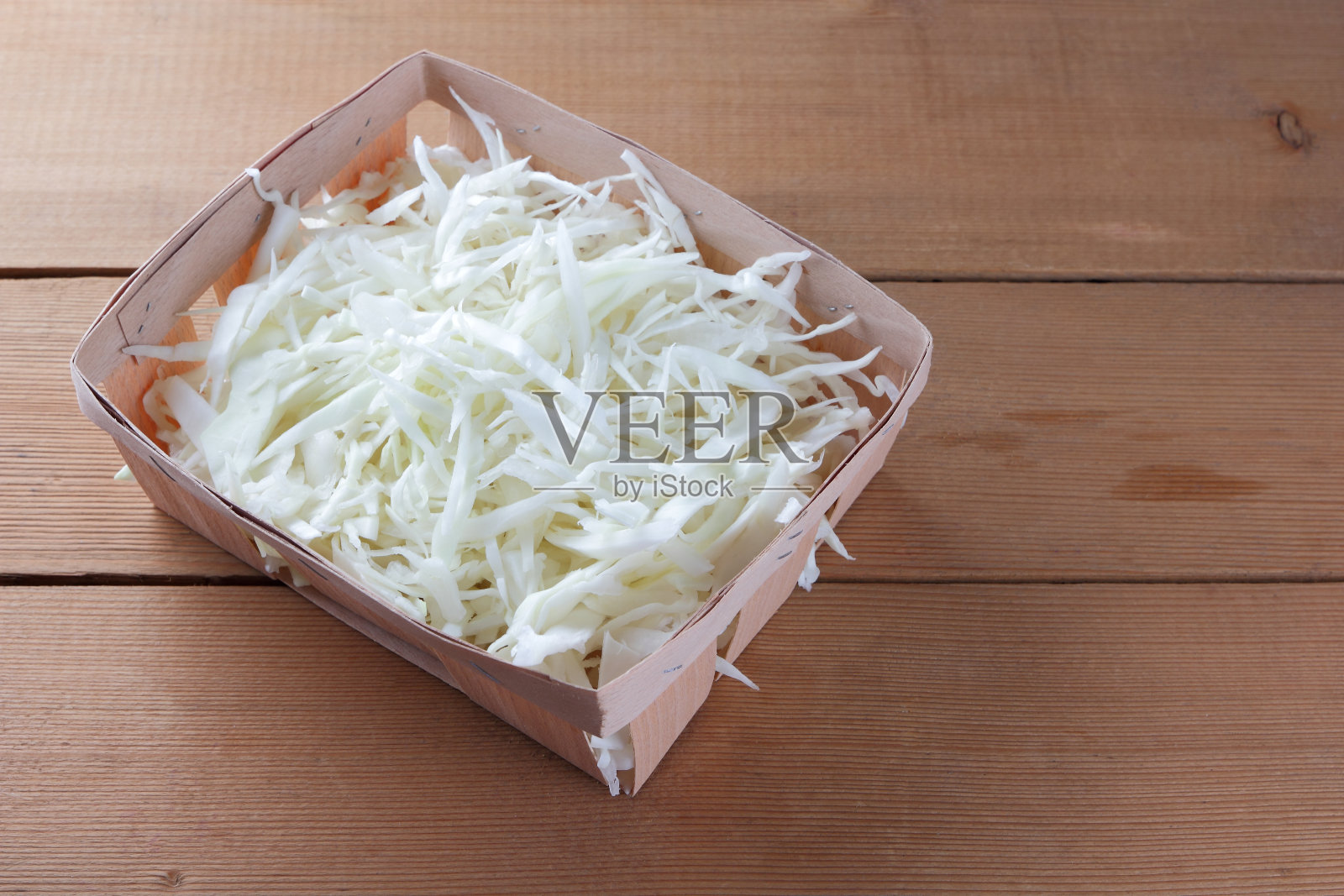 切碎的白色卷心菜在木制的背景下，卷心菜为烹饪在一个木制的盒子，素菜，拷贝空间，新鲜蔬菜在一个家庭厨房，乡村风格照片摄影图片