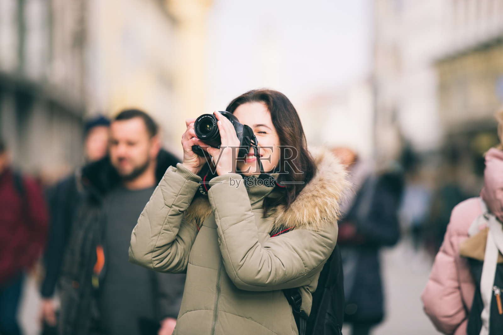 美丽的年轻女游客站在德国慕尼黑的中央街道的背景在冬天。手持黑色大专业相机，微笑拍照照片摄影图片
