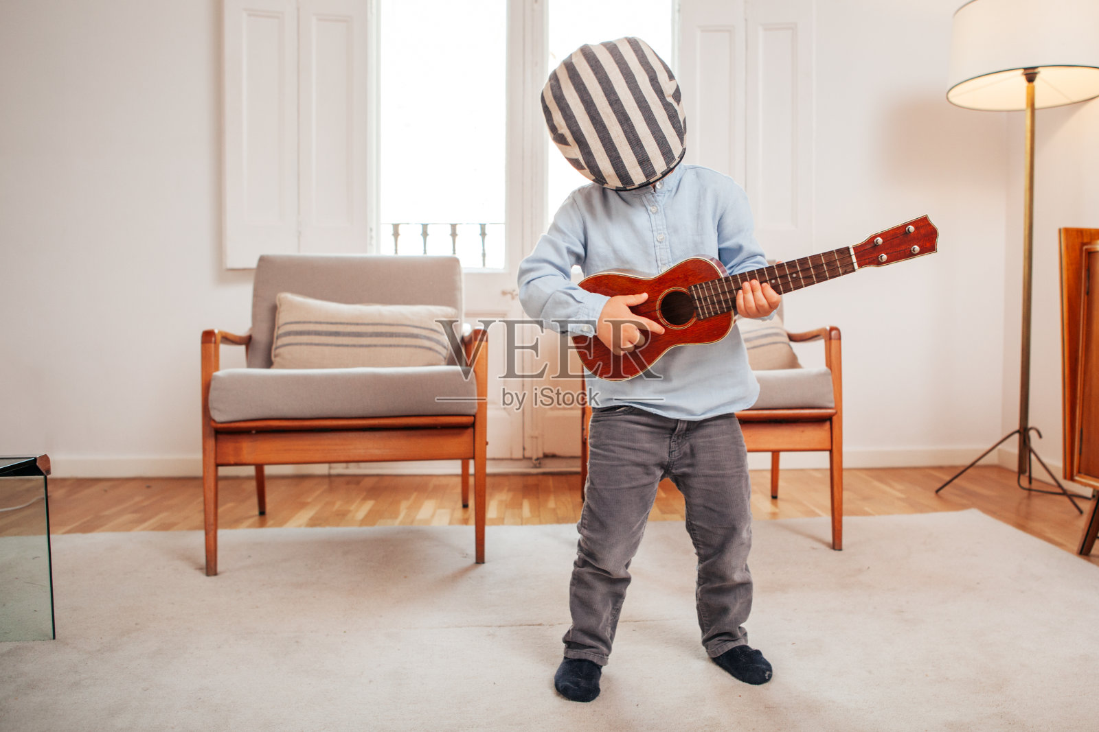一个孩子在客厅里弹奏四弦琴照片摄影图片