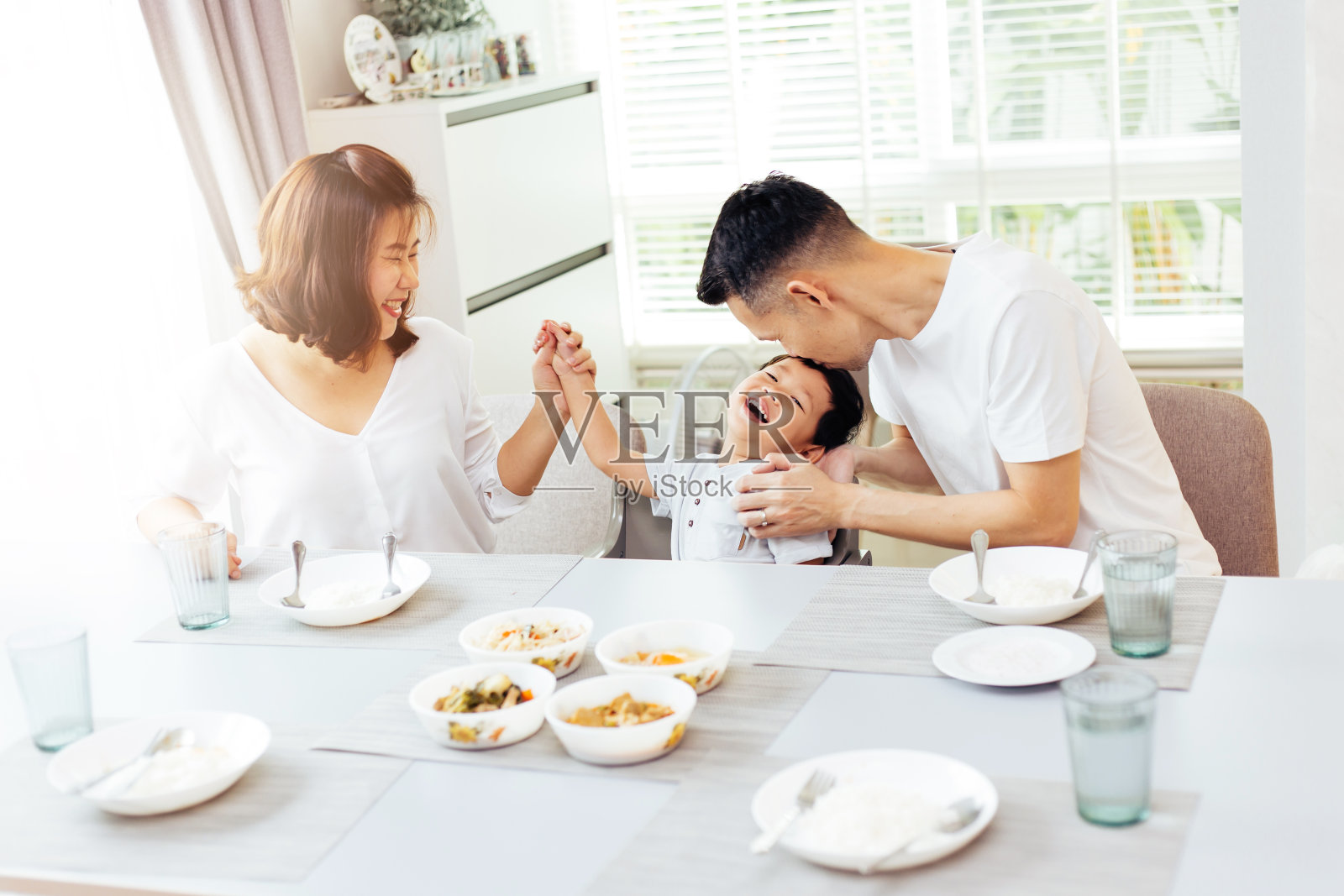 快乐的亚洲家庭，父亲，母亲和儿子玩和欢笑，一边吃晚餐照片摄影图片