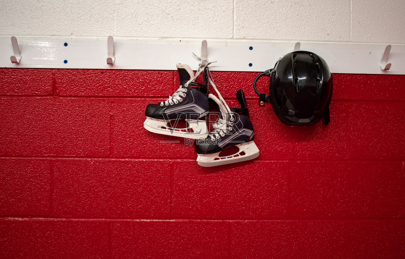 孩子们的曲棍球溜冰鞋和头盔挂在有复印空间的更衣室里照片摄影图片
