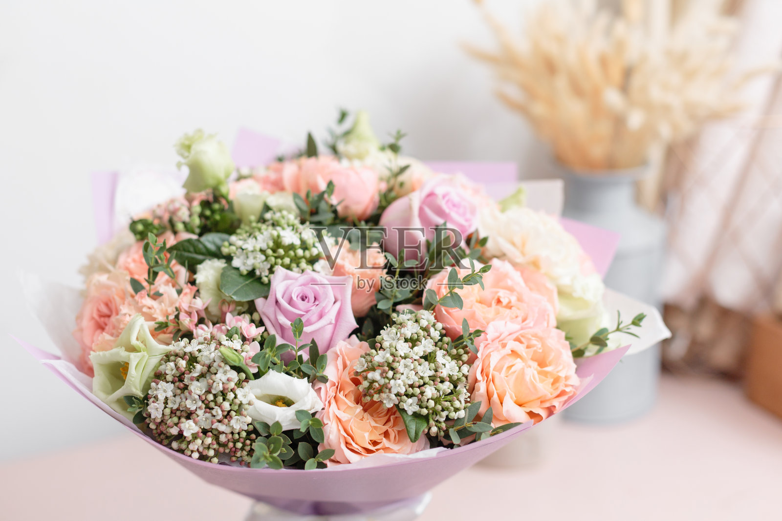 木桌上放着一束美丽的橙色和淡紫色花。花卉栽培技术的概念。春天的颜色。花店花匠的工作。垂直图照片摄影图片