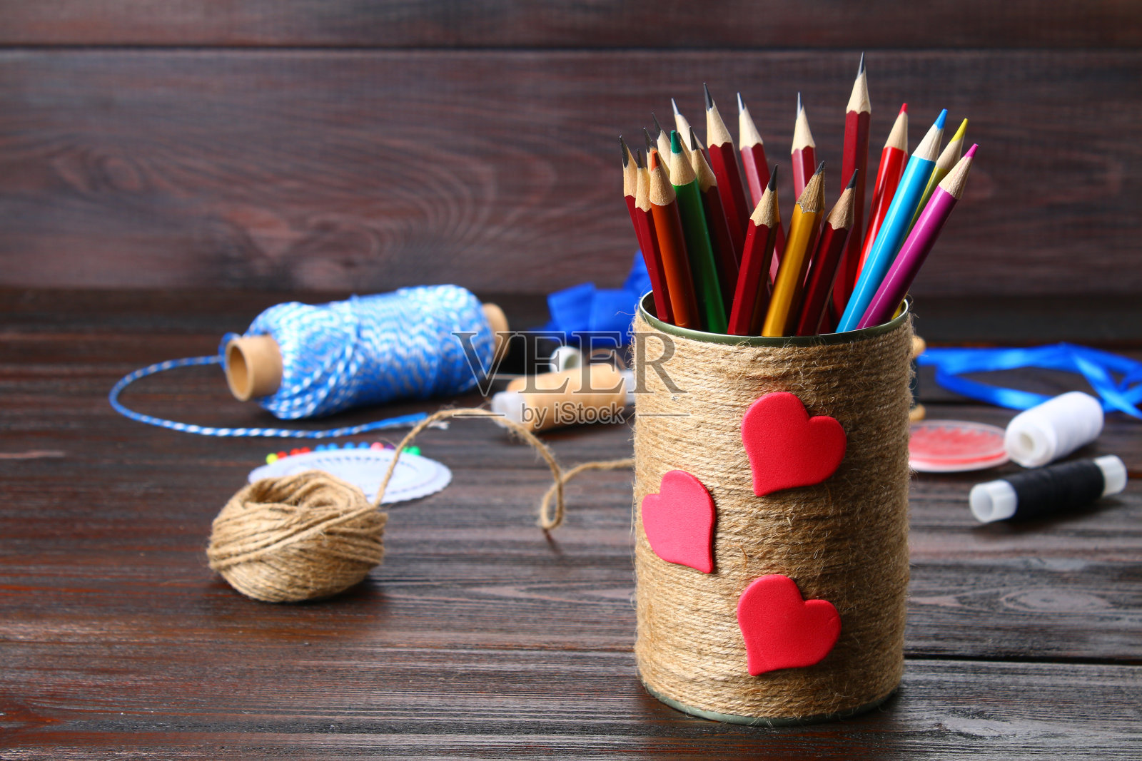 木制桌子上放着用绳子包着心形的铅笔。手工制作的。照片摄影图片
