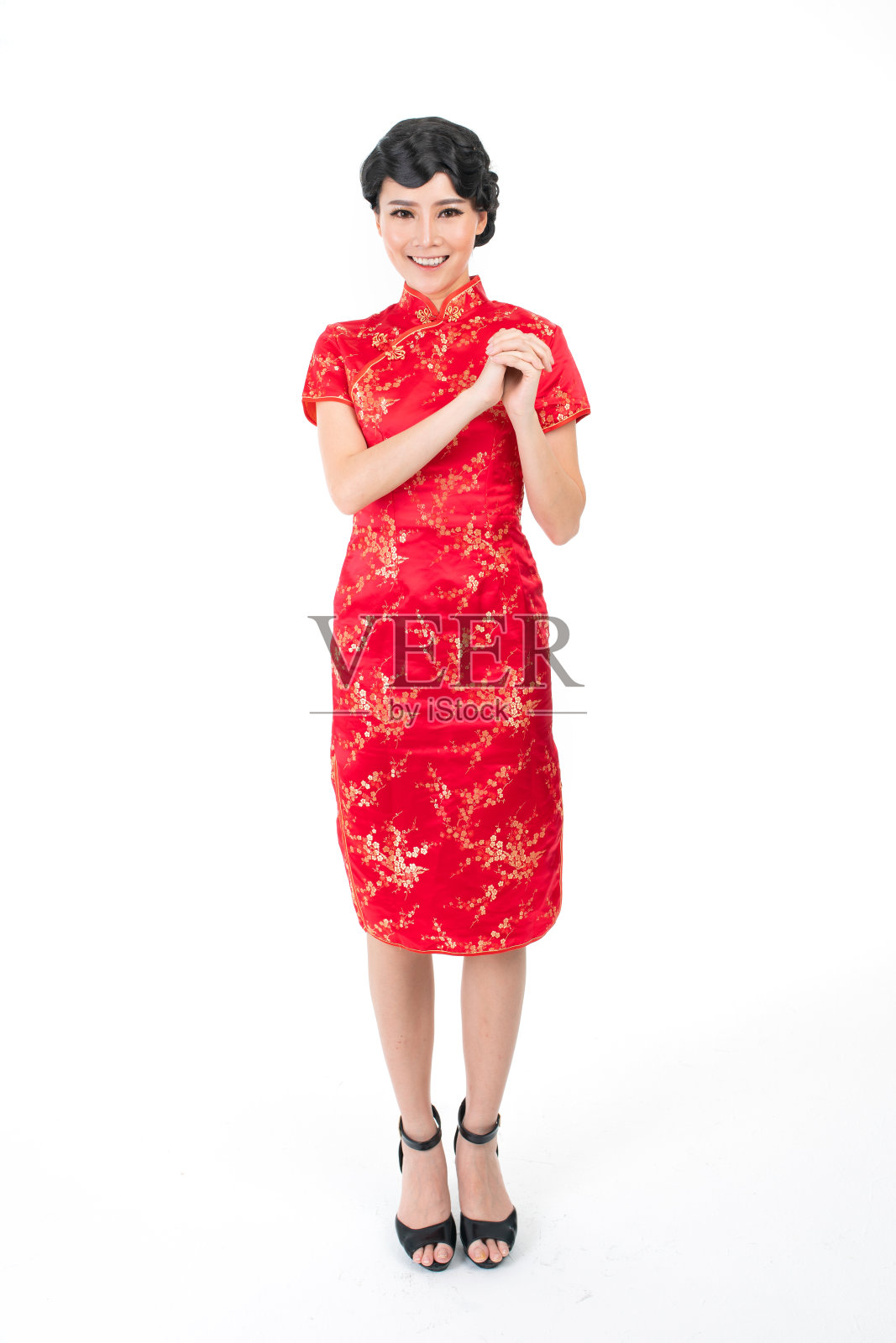 亚洲华人穿着中国传统服装旗袍，摆出中国新年问候的架势照片摄影图片