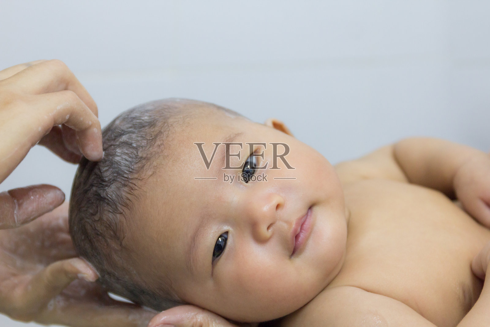 特写亚洲可爱的婴儿新生儿洗澡与手母亲。照片摄影图片