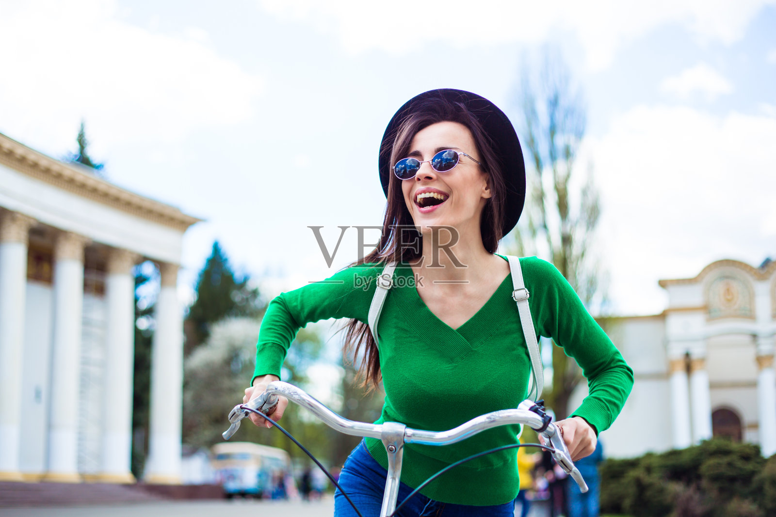 快乐美丽的年轻时髦的女孩骑着复古自行车在城市周围玩照片摄影图片