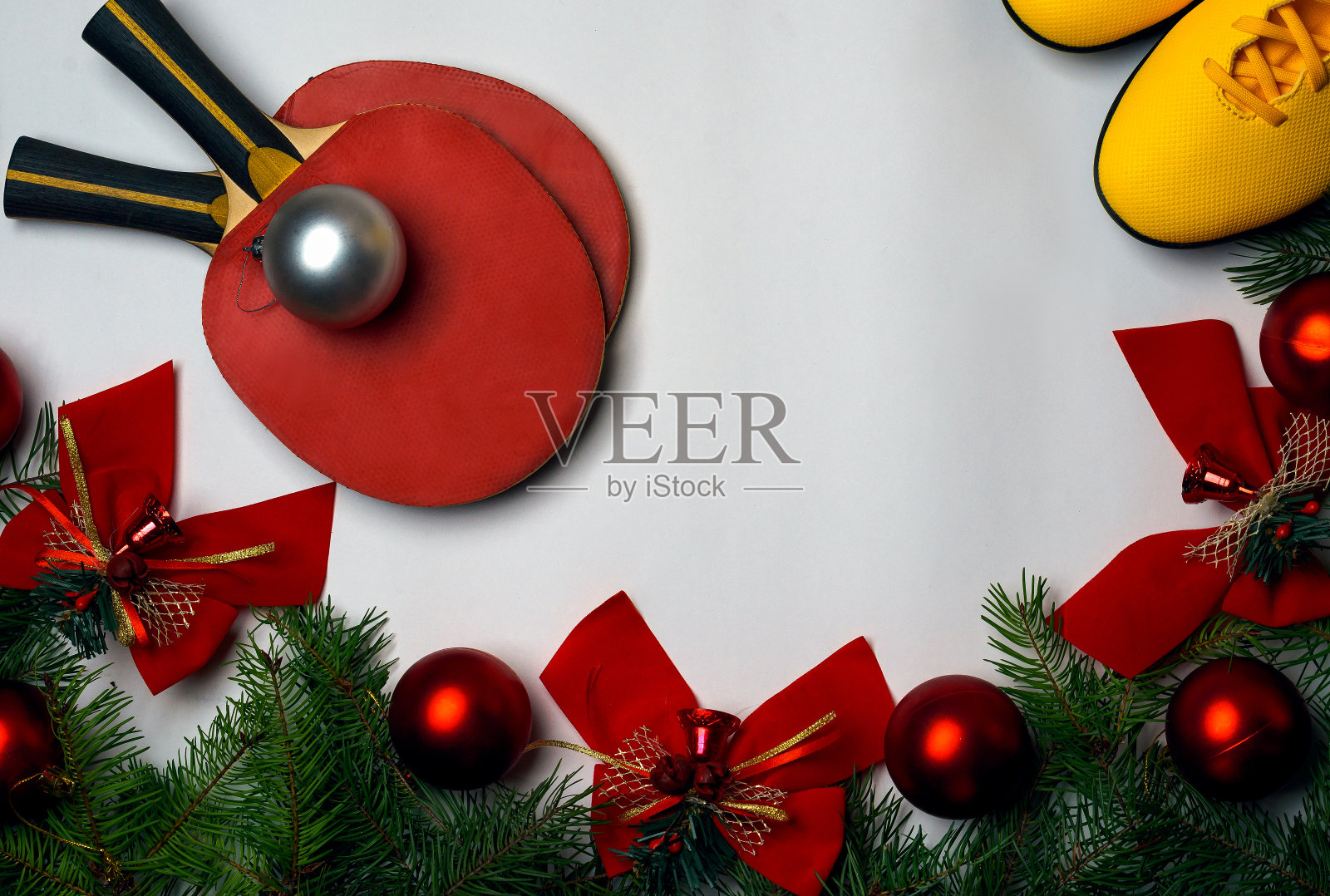 健身，健康和积极的生活方式贺卡的概念。圣诞节和新年的背景与绿色的树枝冷杉树红色的玻璃球和红色的蝴蝶结铃铛在白色的背景和黄色的运动鞋和红色的网球拍。本空间照片摄影图片