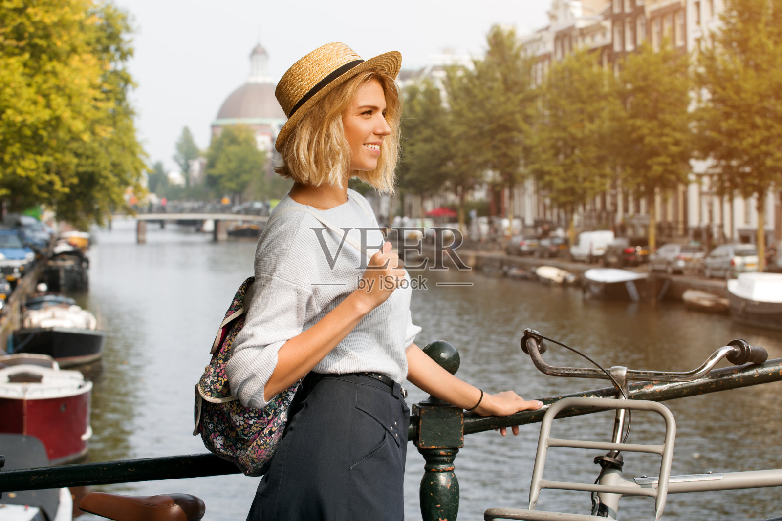 快乐的旅行者女孩享受阿姆斯特丹城市。微笑的女人看着一边的阿姆斯特丹运河，荷兰，欧洲照片摄影图片