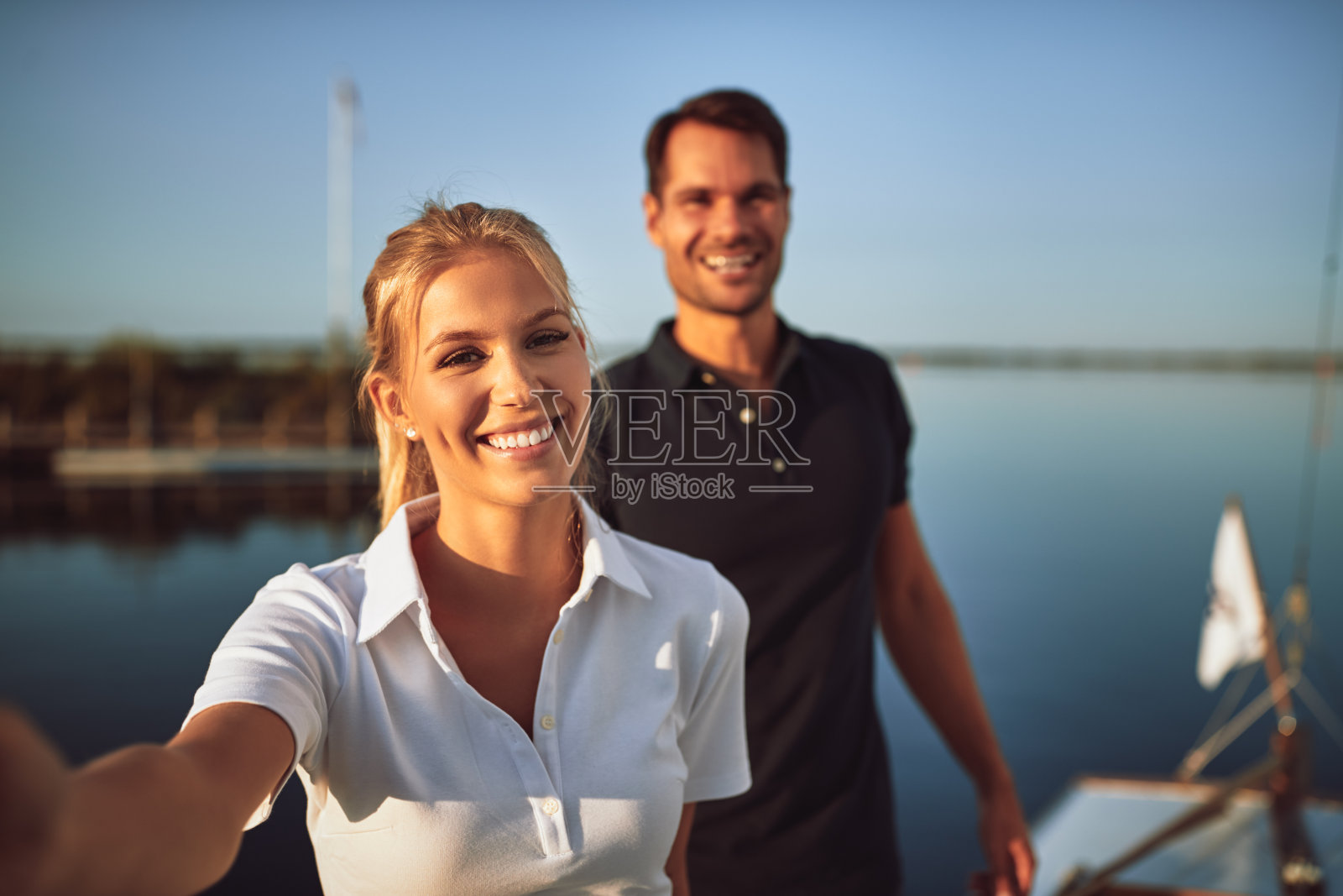 年轻夫妇微笑着站在他们的游艇上照片摄影图片