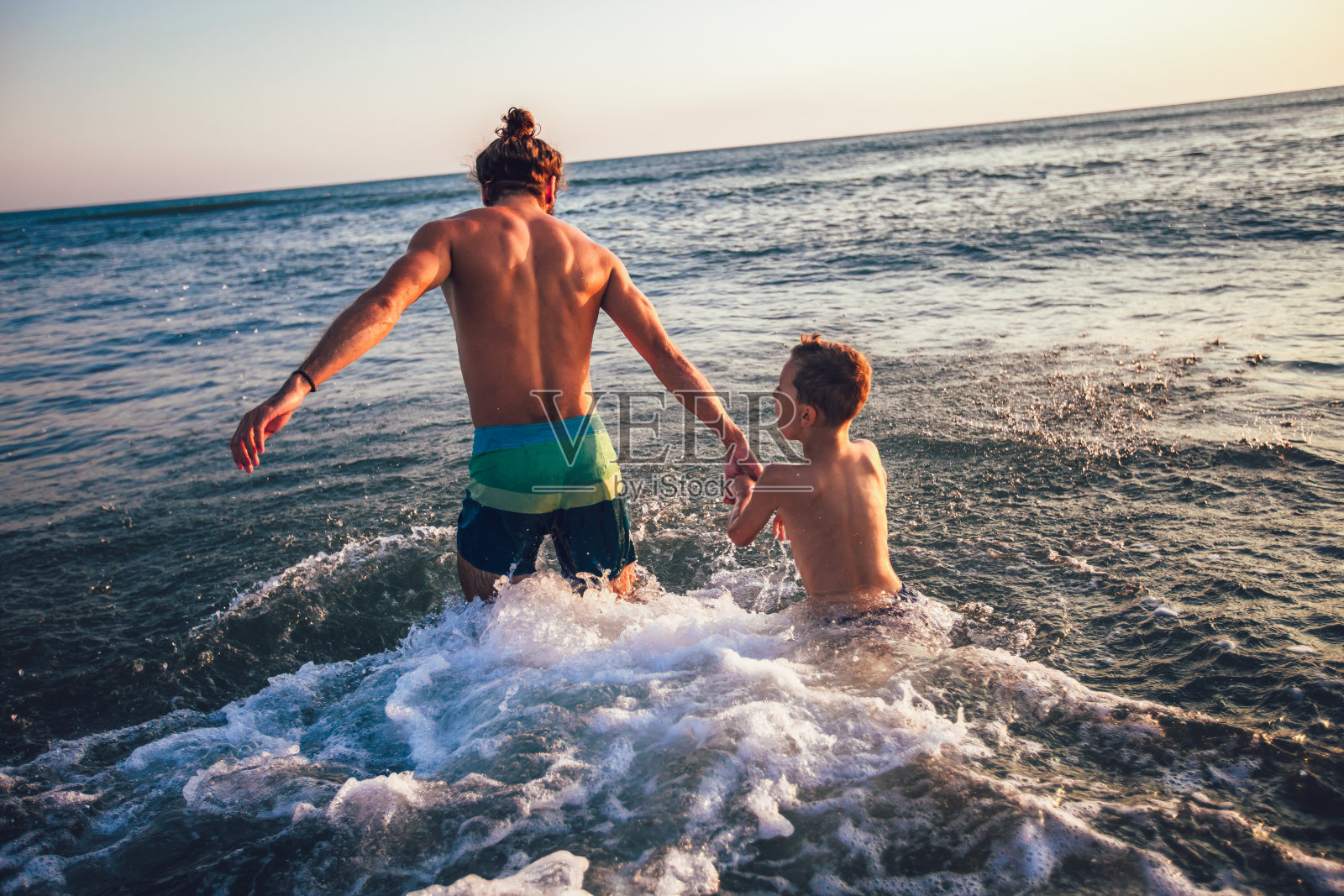 父亲和儿子白天在海滩上玩照片摄影图片
