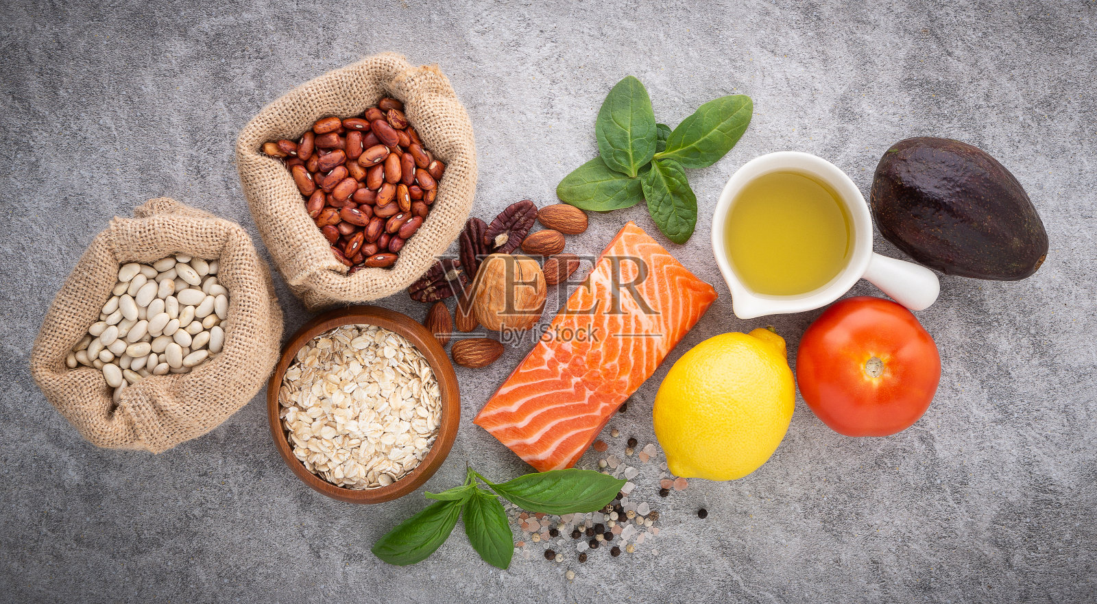 健康食品的选择。鲑鱼，坚果，盐，胡椒，水果和蔬菜的石头背景从俯视图。照片摄影图片