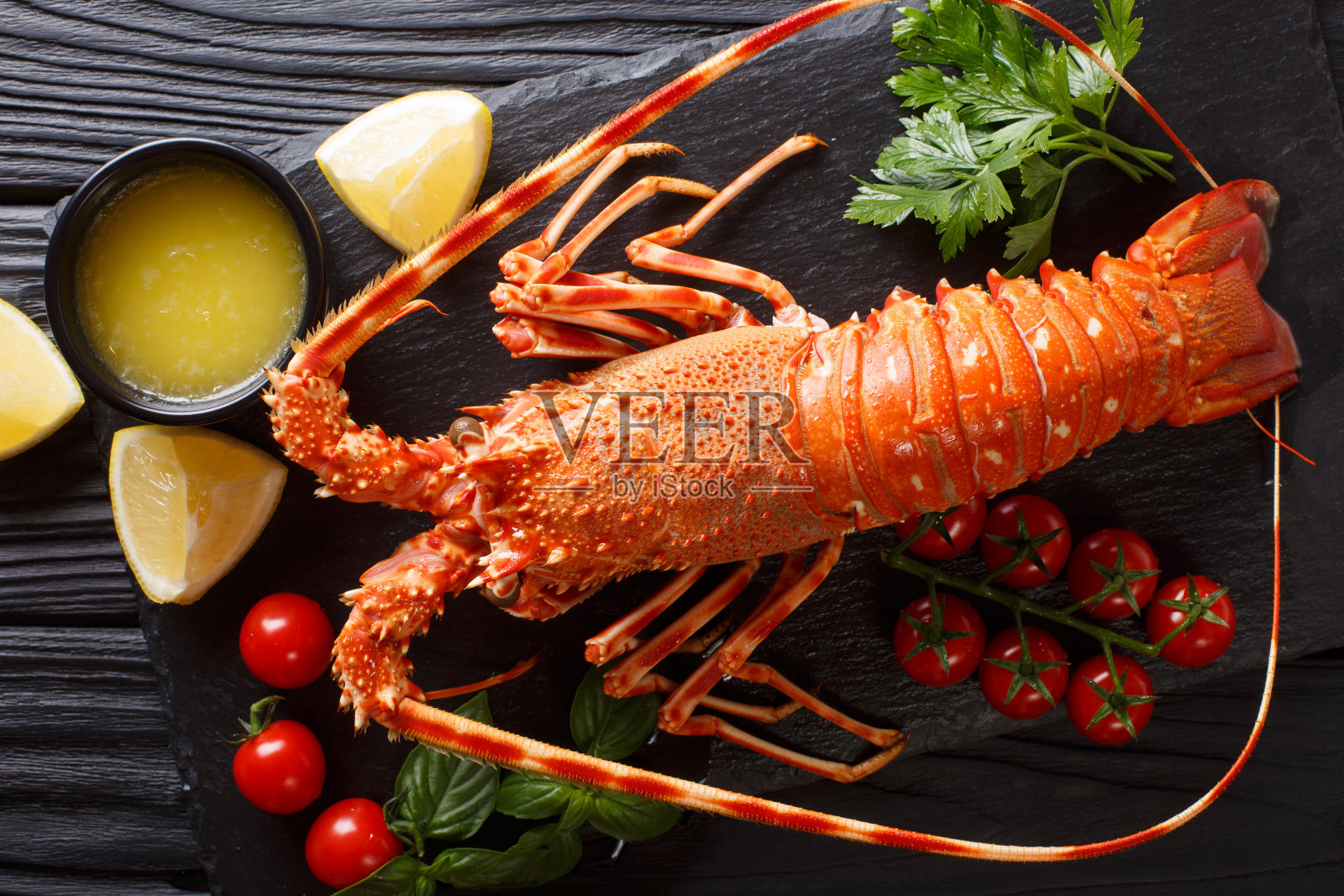 美味食物:煮多刺或岩龙虾配西红柿，柠檬和融化的黄油特写。水平的俯视图照片摄影图片