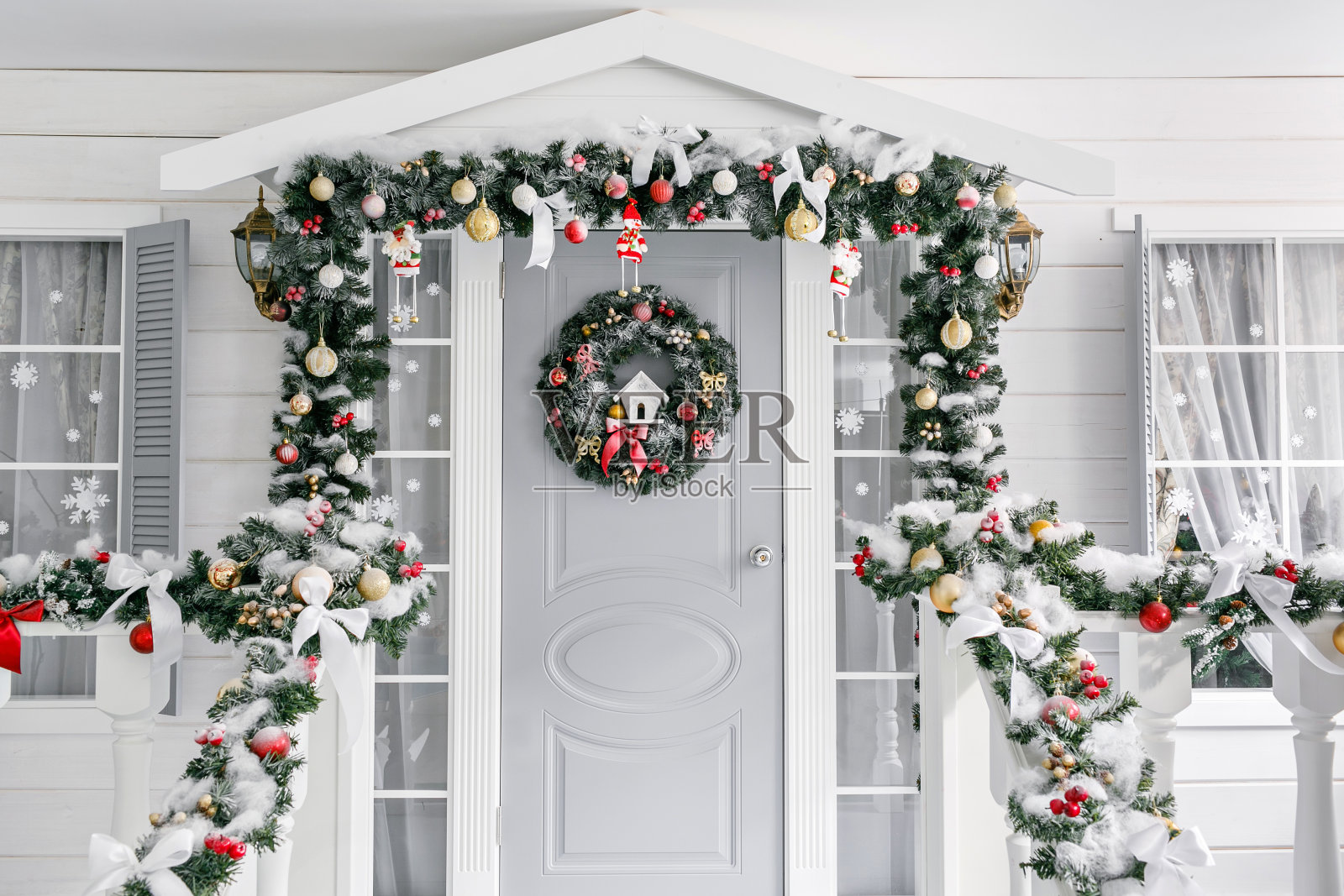 圣诞节的早晨。门廊一间门上装饰有圣诞花环的小房子。冬天的童话。照片摄影图片