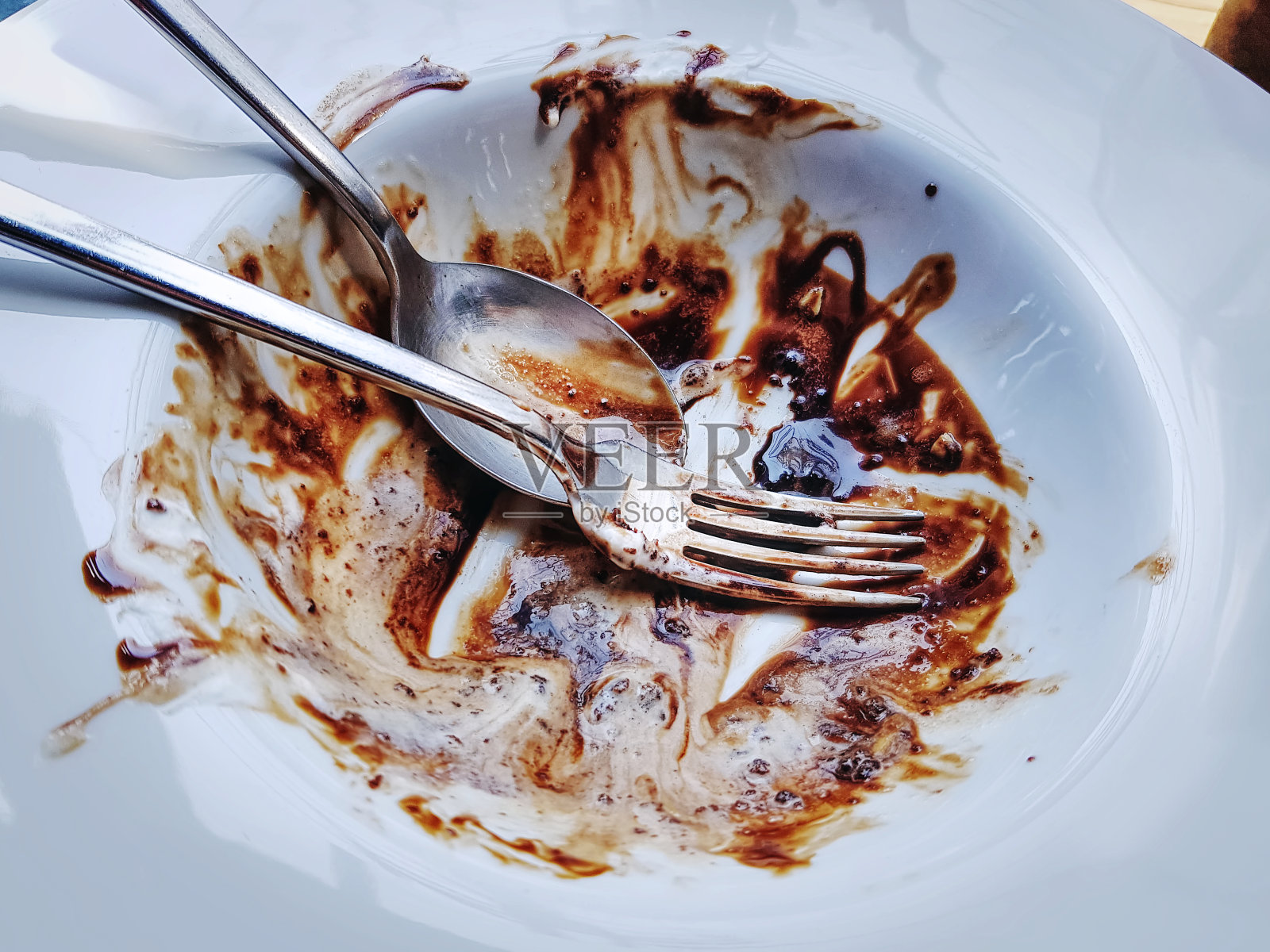 高角度的勺子和叉子与巧克力剩余的白色盘子照片摄影图片