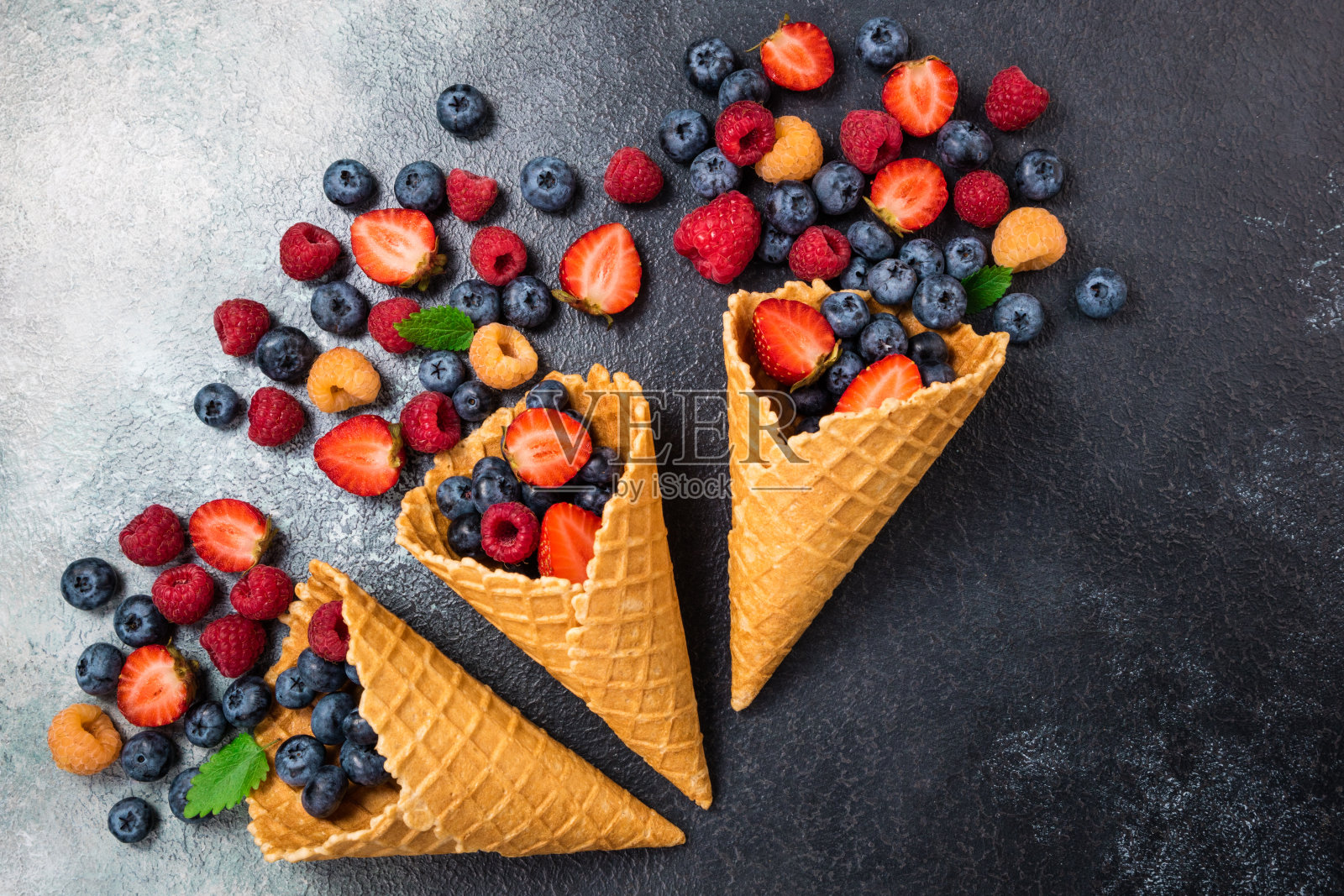 甜筒里的新鲜浆果。甜点是草莓、覆盆子、蓝莓。健康饮食、节食食品和营养的概念。夏天的背景照片摄影图片