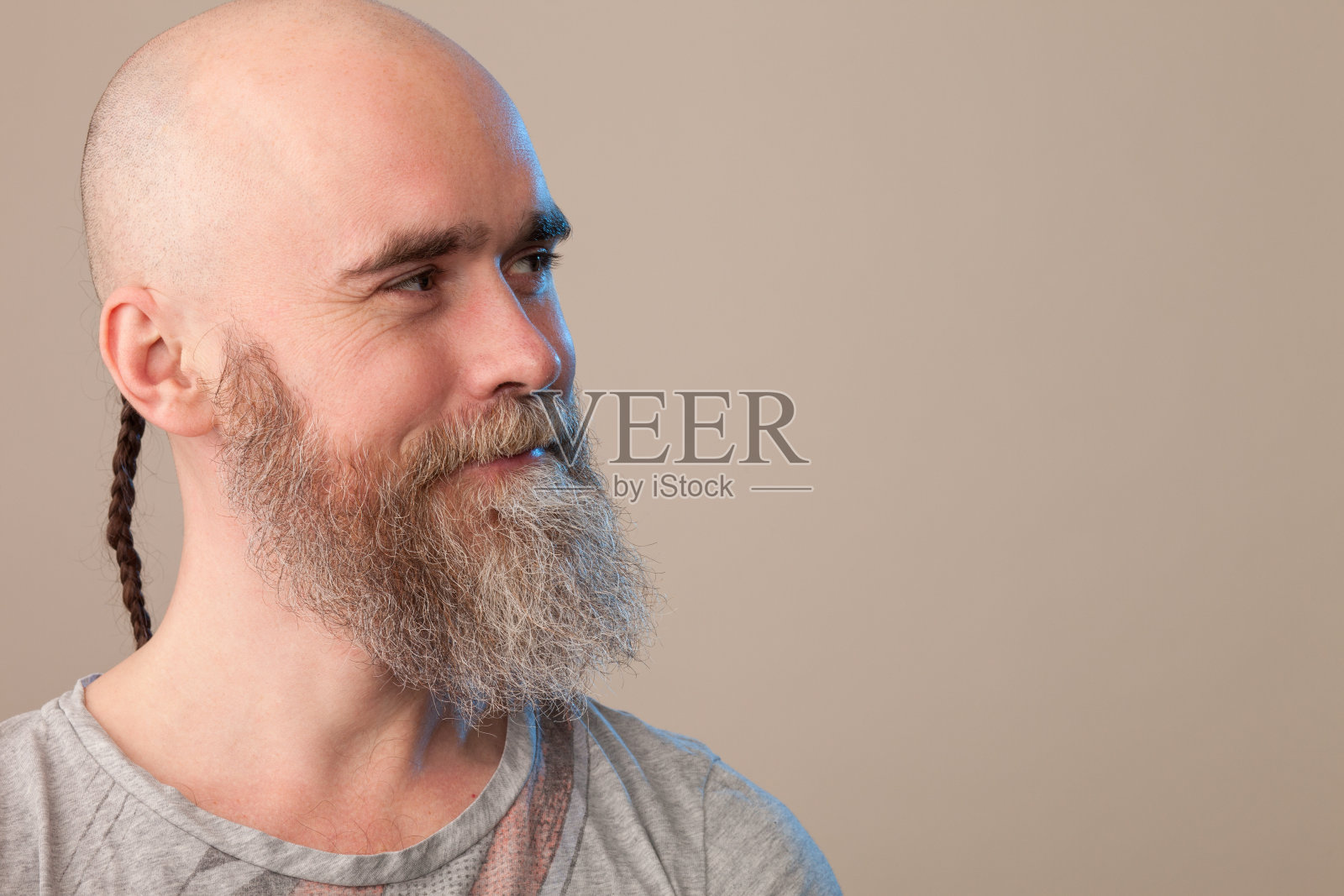 一名40岁剃着光头的大胡子男子的工作室肖像，他穿着一件米色背景的t恤照片摄影图片