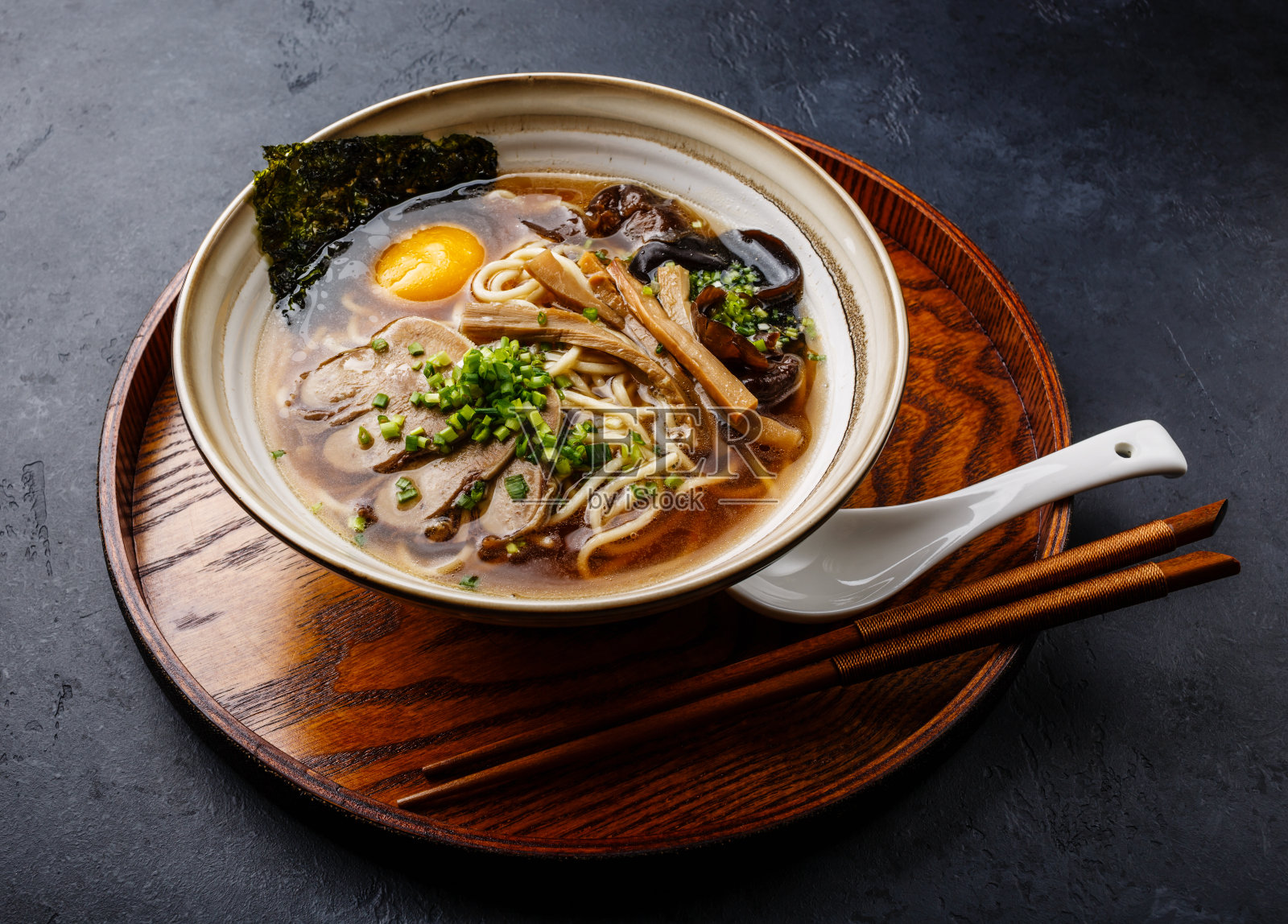 亚洲拉面汤，牛舌肉，蘑菇和生蛋黄在碗中，黑色背景照片摄影图片