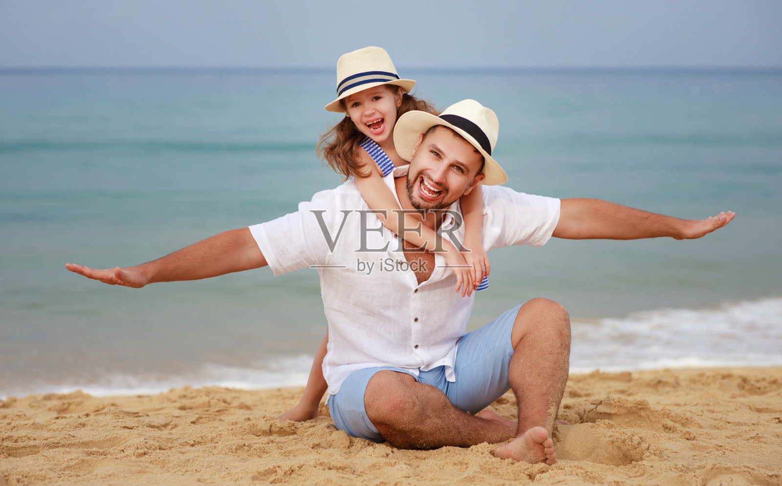 幸福的家庭在海滩。父亲和女儿在海上拥抱照片摄影图片