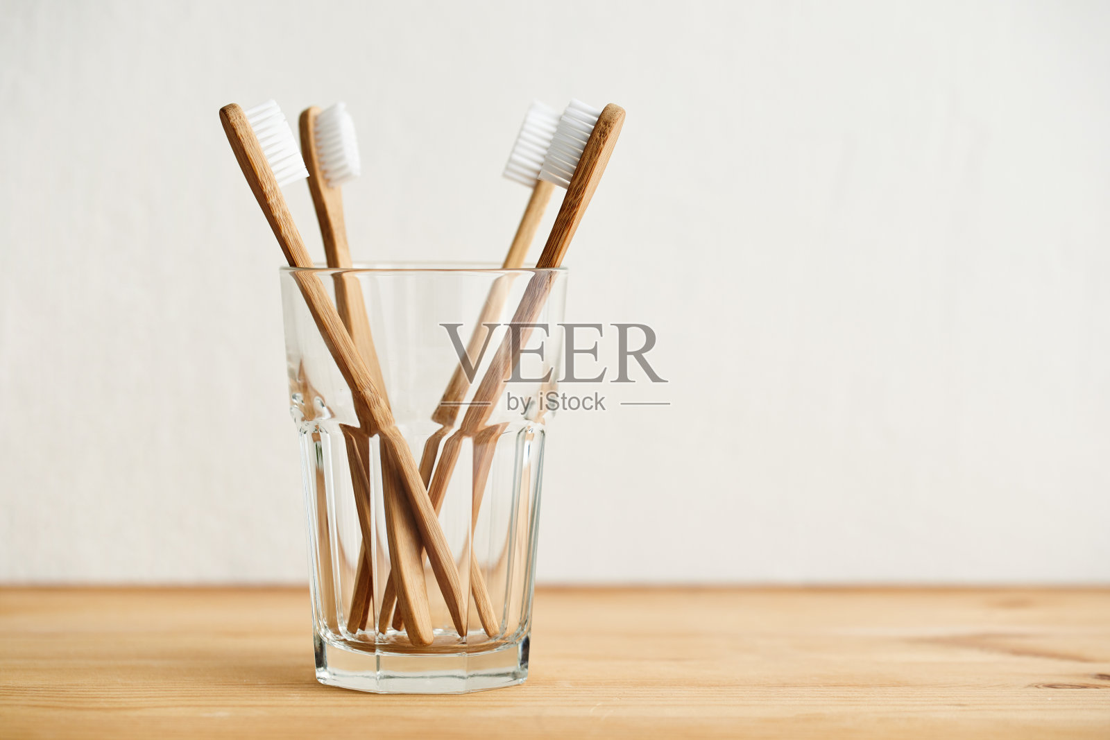 四把竹牙刷装在玻璃杯里放在一张木桌上照片摄影图片