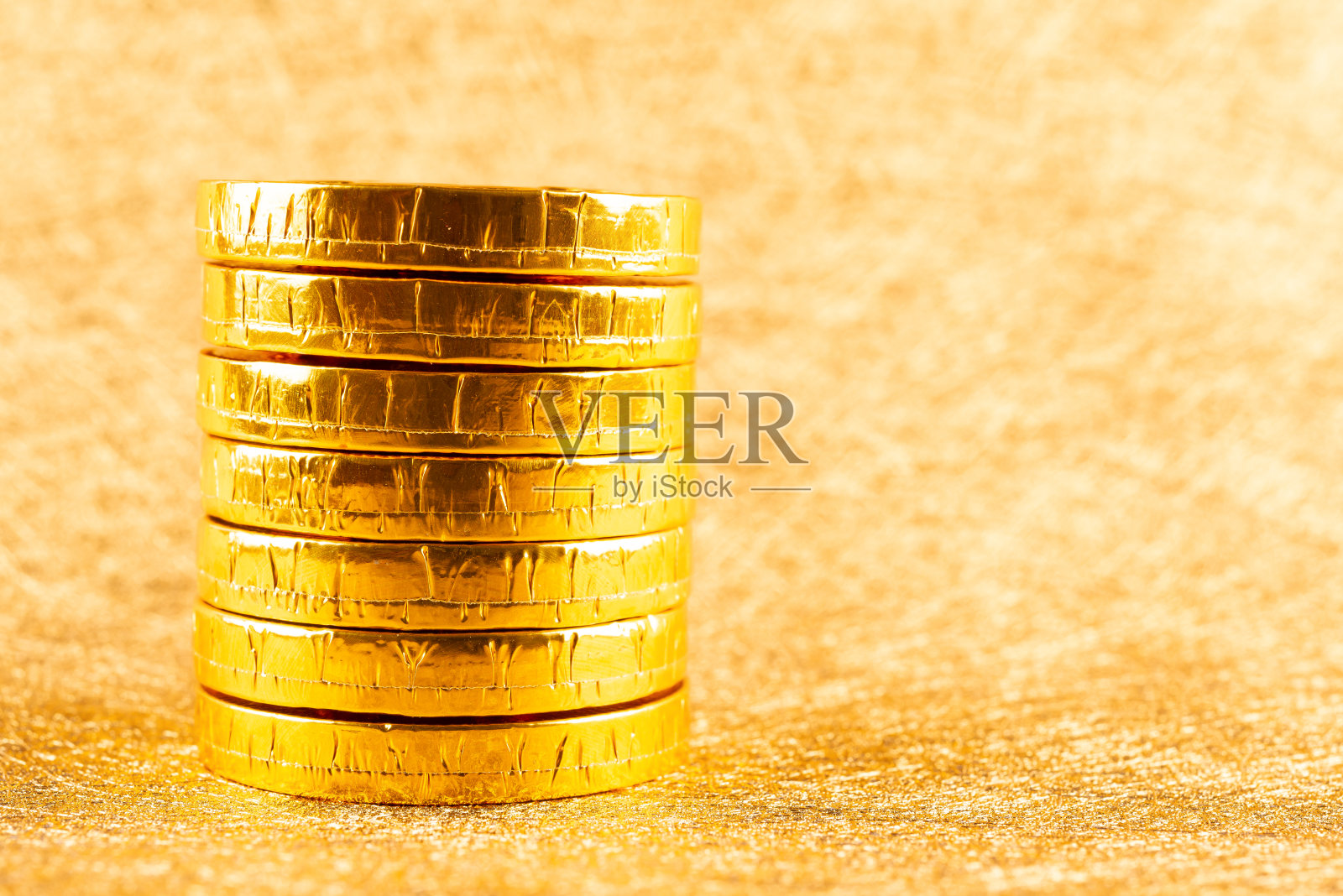 巧克力硬币堆积在金色的背景上照片摄影图片
