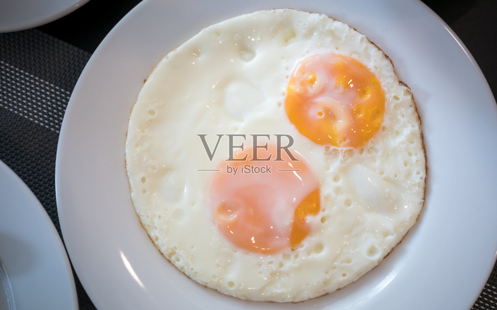 早餐桌上白色的盘子里有两个煎蛋照片摄影图片