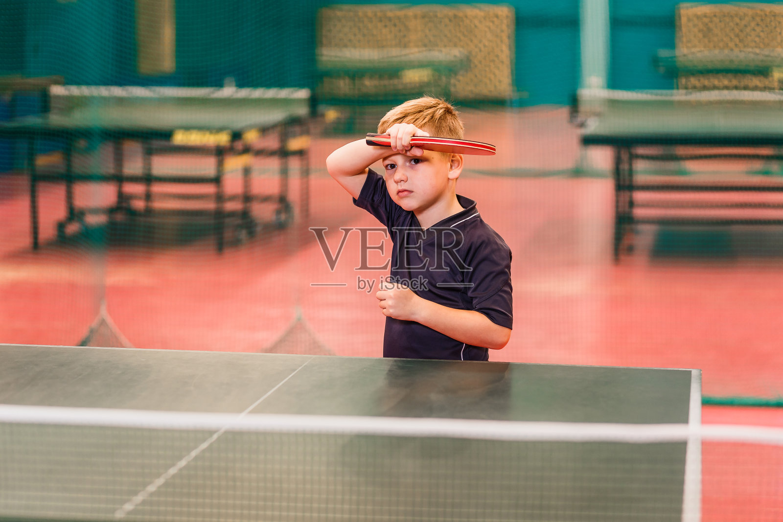 一个穿着灰色t恤的男孩打乒乓球打得很好照片摄影图片