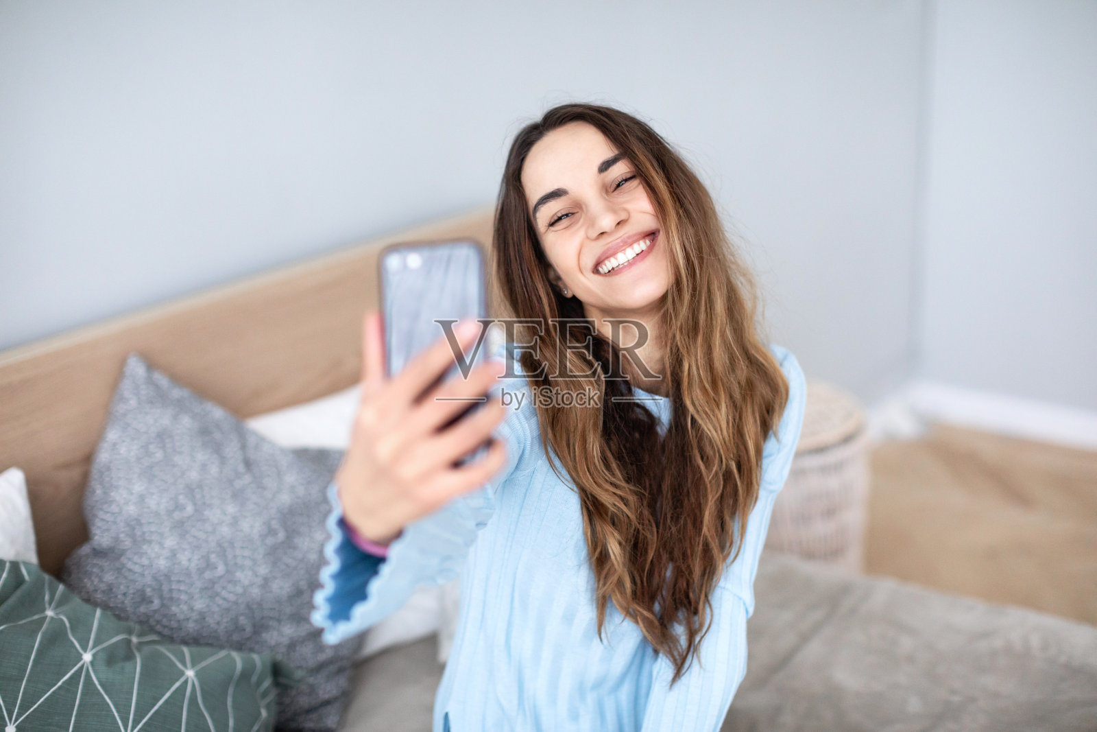 漂亮微笑的女人在家里用智能手机自拍。照片摄影图片