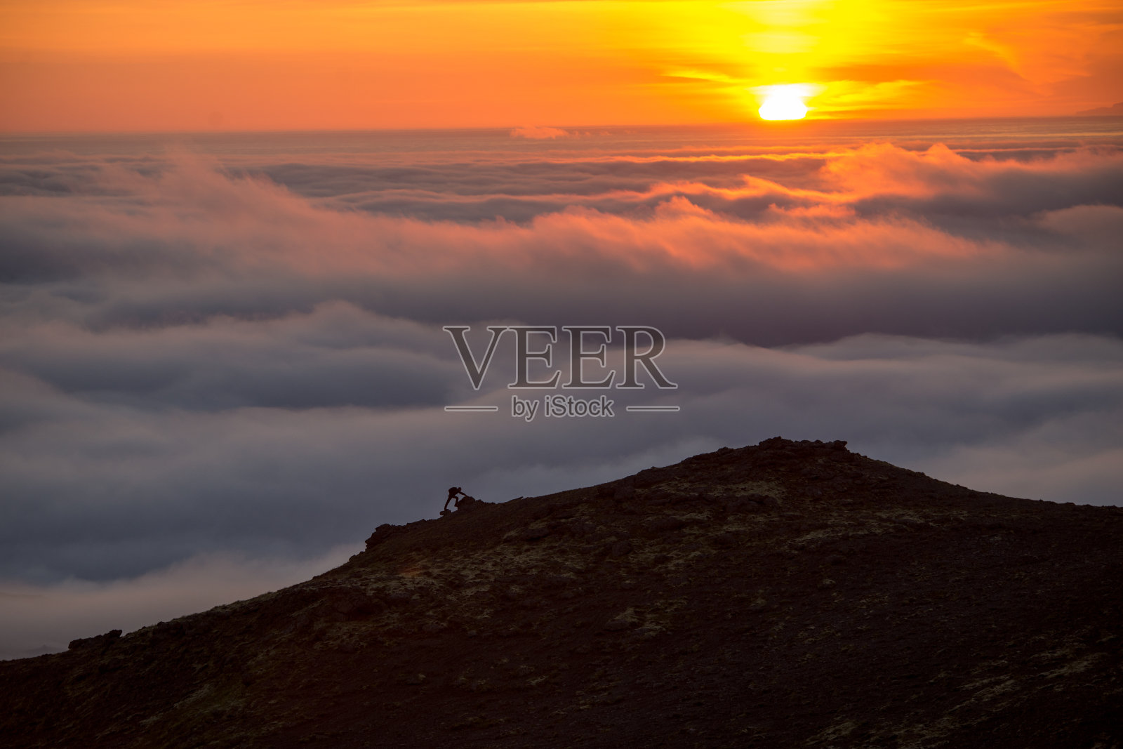 一个男人的剪影在山脊之上的云海，朦胧的山在日落在冰岛照片摄影图片