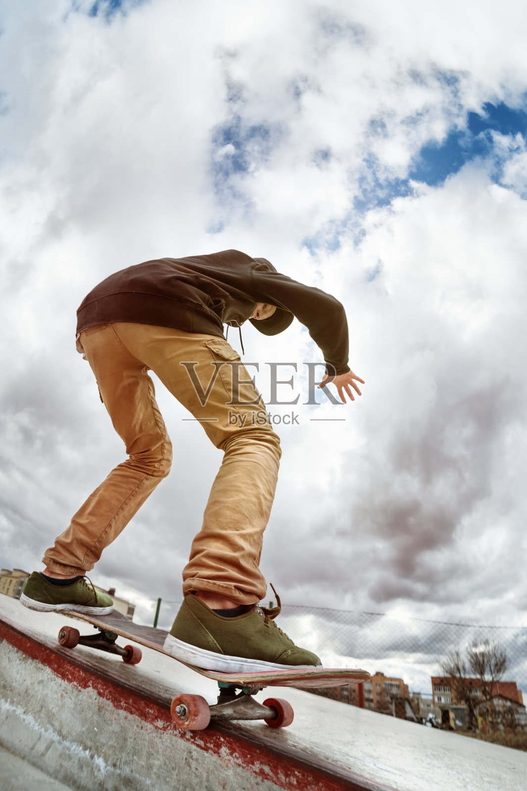 十几岁的溜冰者在一个滑板公园里，穿着连帽运动衫和牛仔裤滑过滑板的栏杆照片摄影图片