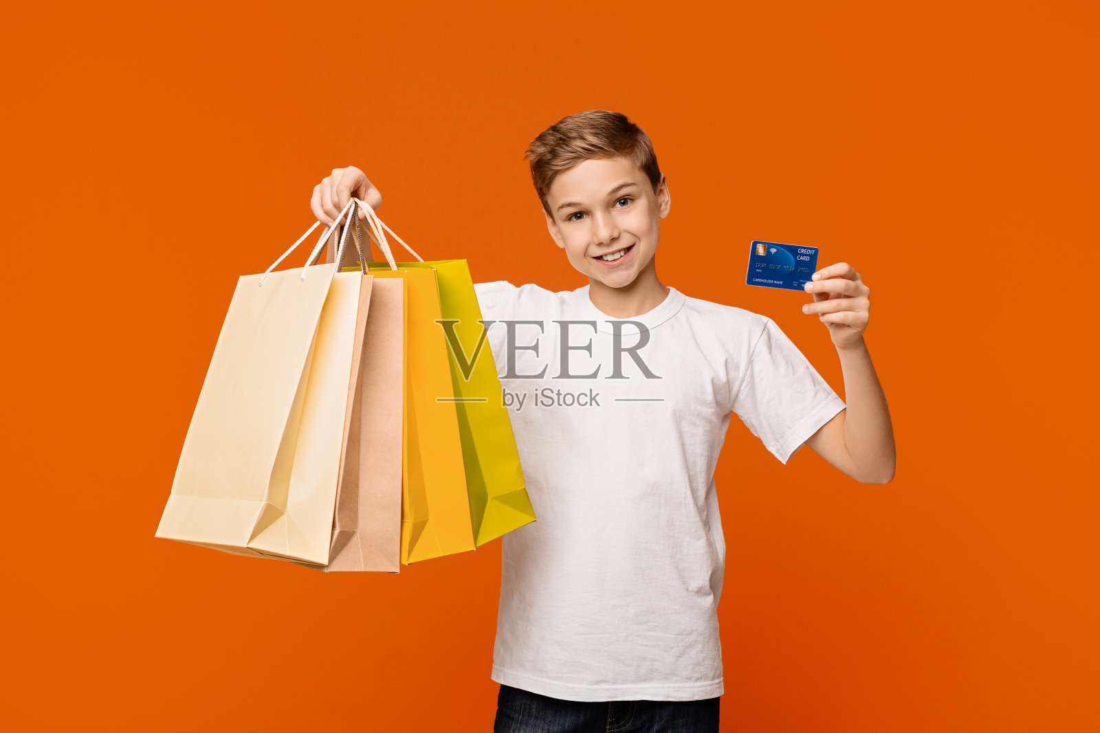男孩展示他的购物袋和信用卡或借记卡照片摄影图片