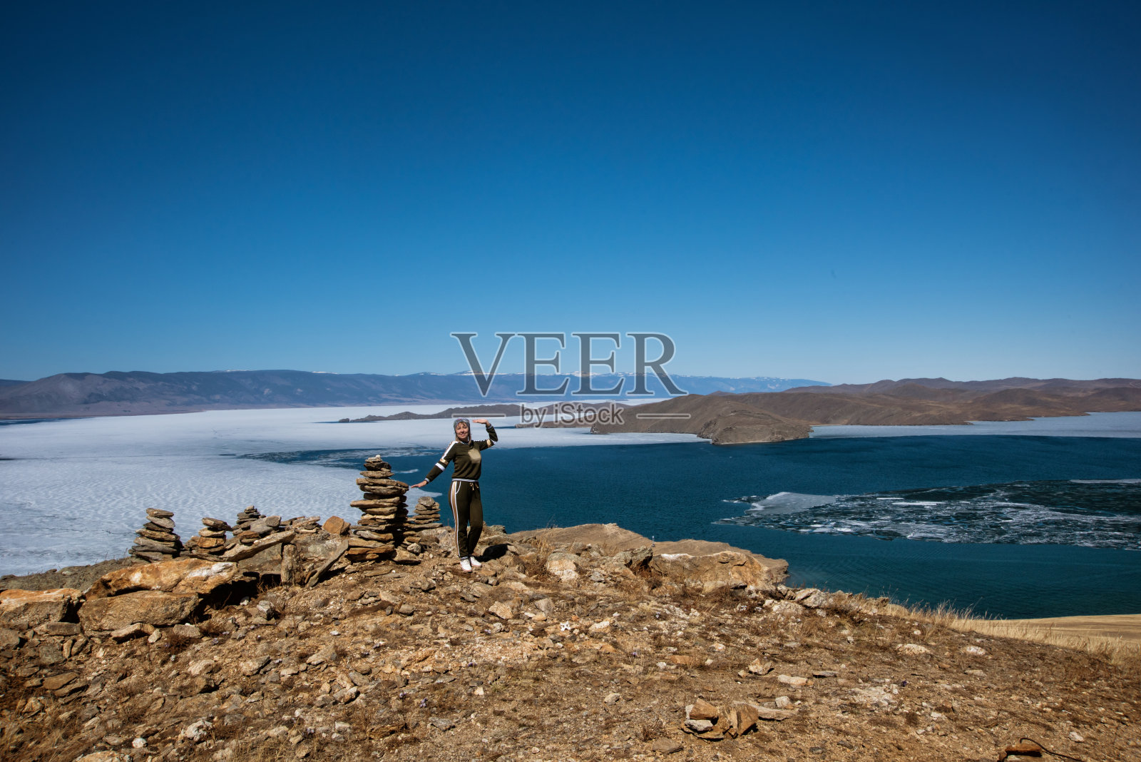 俯瞰美丽的贝加尔湖，浮冰漂浮在水面上，女孩站在岩石附近，俄罗斯照片摄影图片