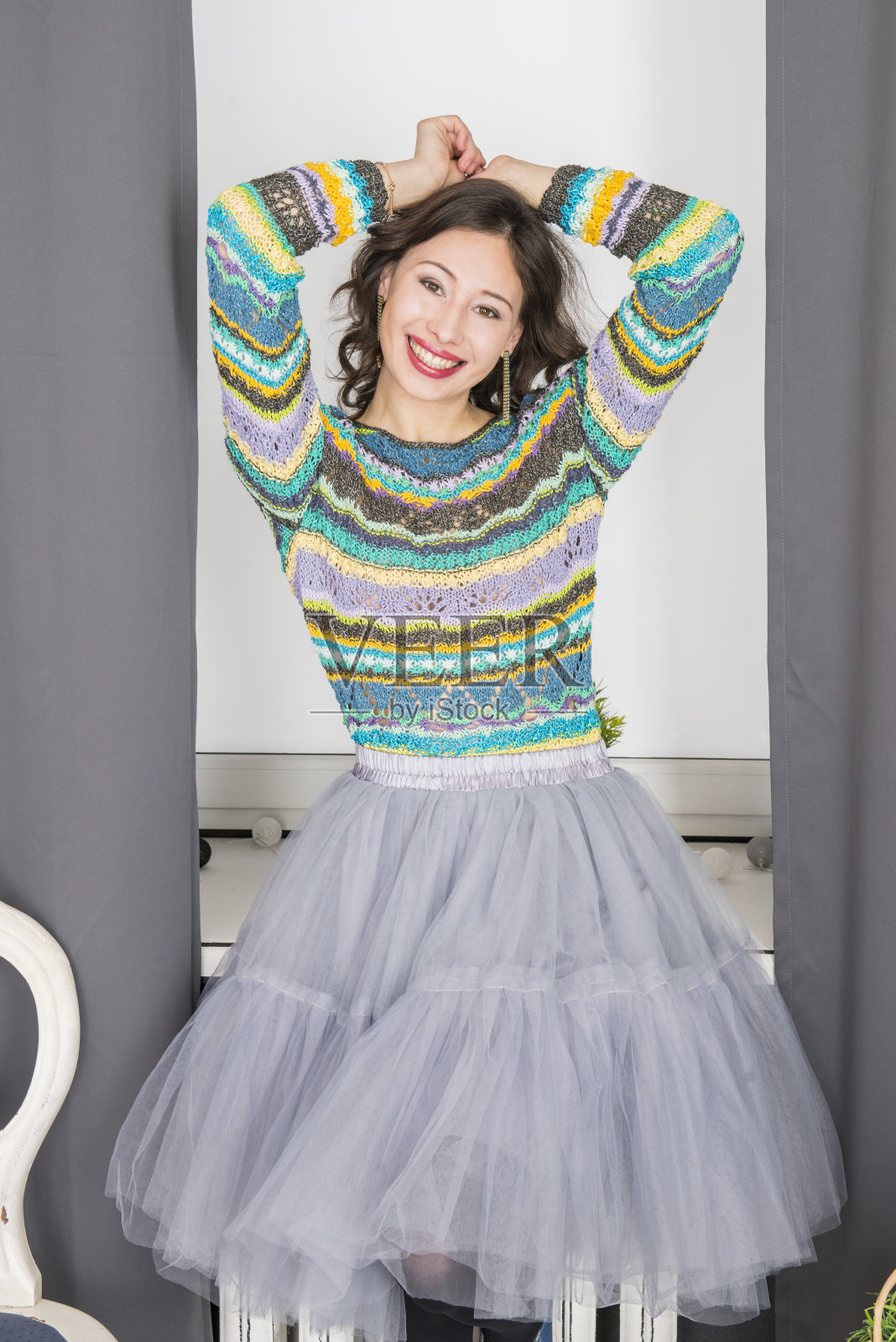 这个快乐的女人穿着一件手工毛衣在室内摆姿势，这是一件用针编织的时髦套衫照片摄影图片