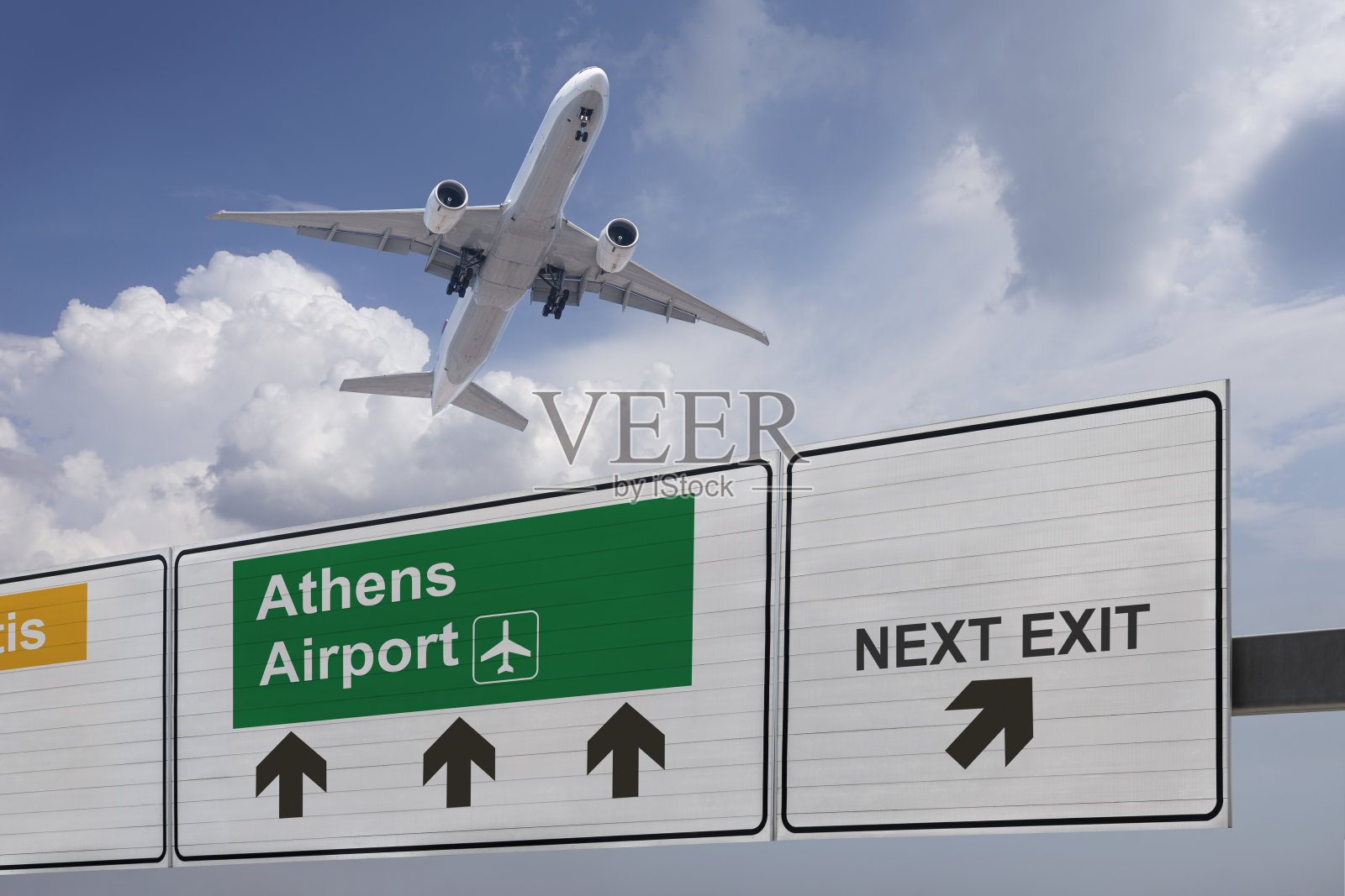 指示雅典机场方向的路标和一架刚起飞的飞机。照片摄影图片