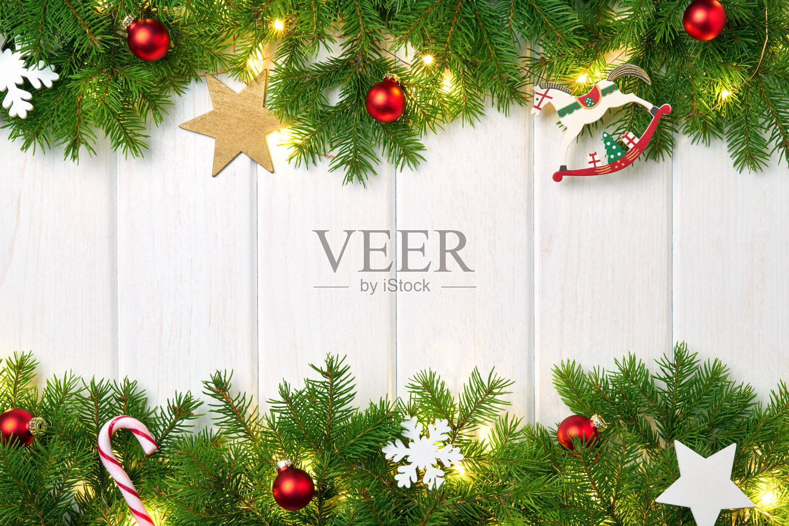 圣诞相框贺卡。在白色的背景上刷一根圣诞树的树枝，上面有红色的球和闪亮的星星、小时、雪花、糖果和圣诞彩灯的花环照片摄影图片