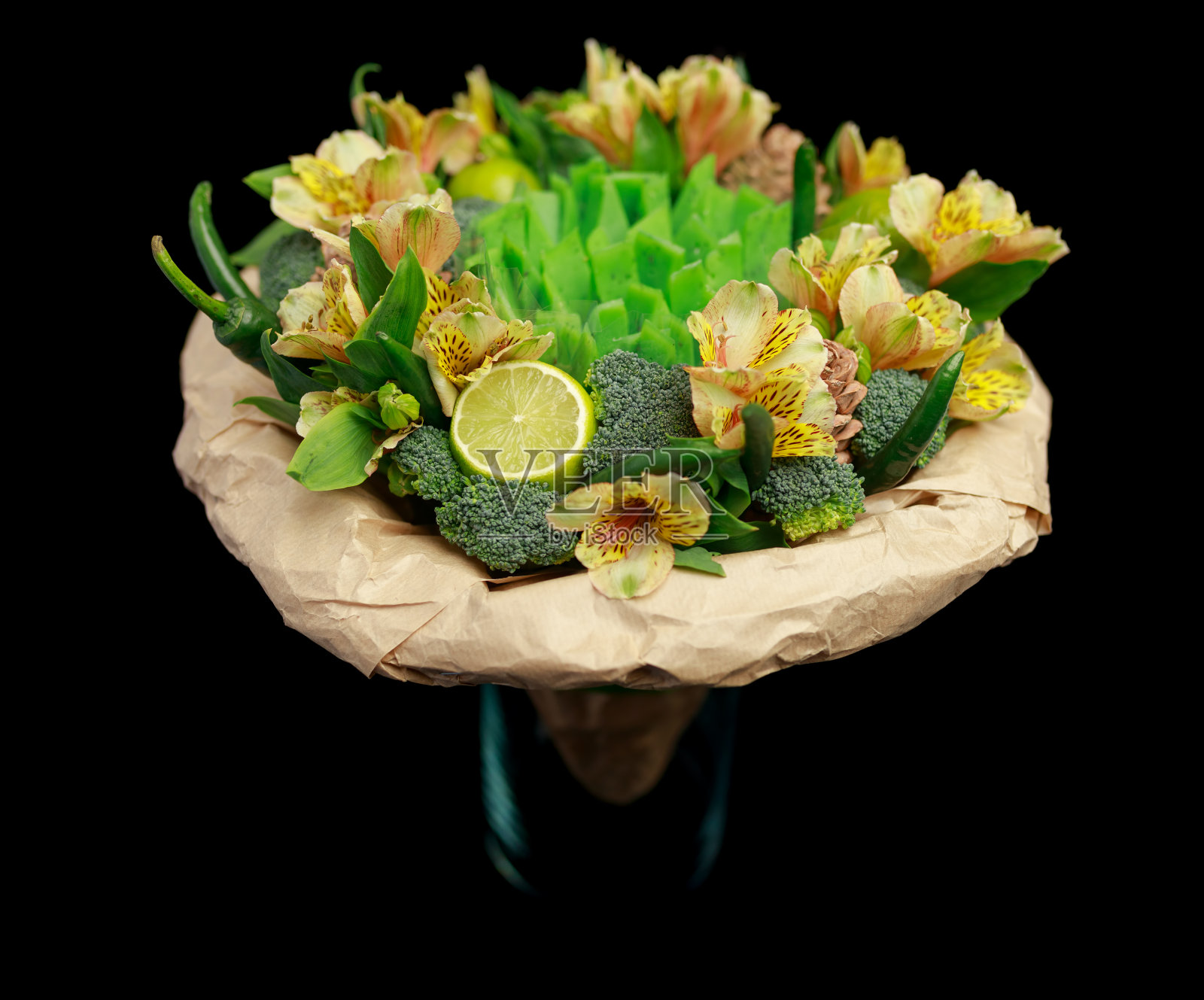 最初的礼物是一束鲜花、蔬菜和绿色奶酪，放在一个玻璃花瓶里，孤立在黑色的背景上照片摄影图片