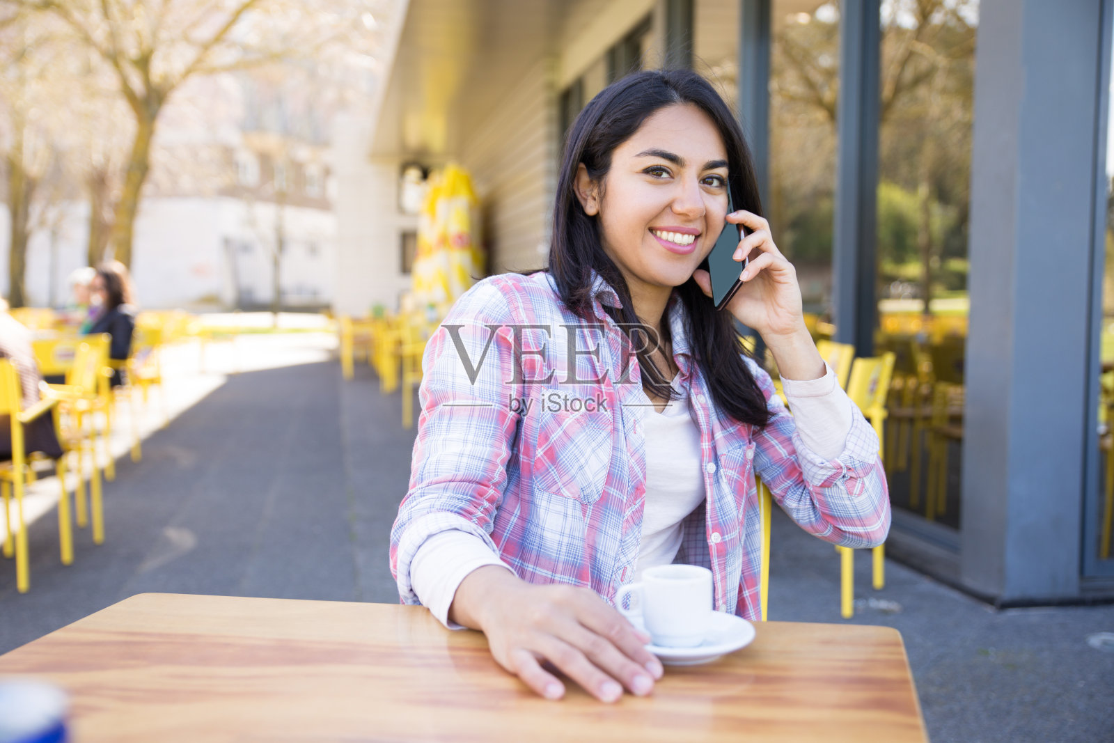 一个快乐的女人，一边打电话一边在街头咖啡馆喝咖啡照片摄影图片