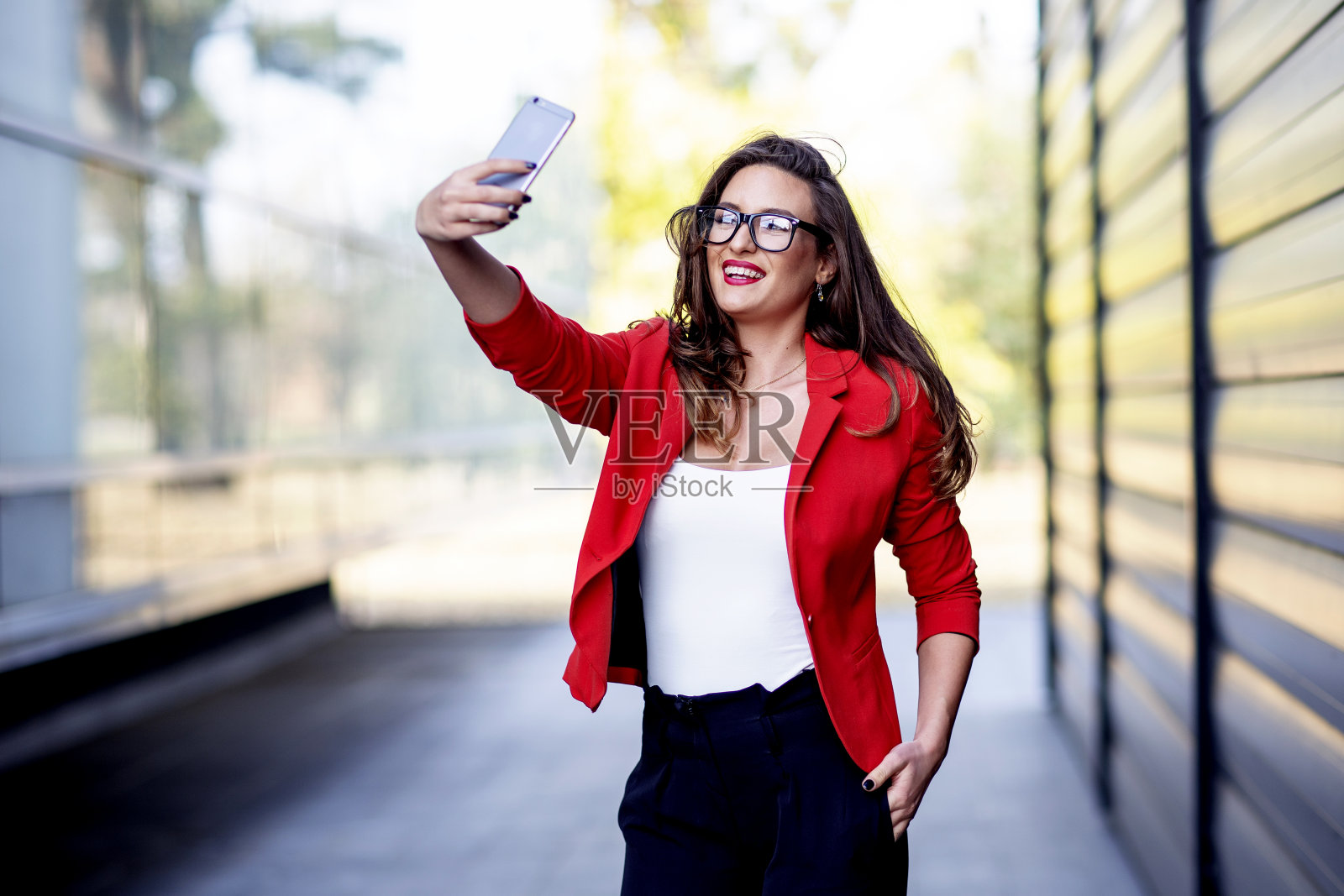 长发美丽的商业女人在办公室前用手机自拍照片摄影图片